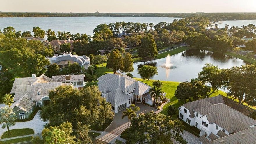 Welcome to 9138 Great Heron Circle, !!!!!!! SELLER FINANCING AVAILABLE !!!!!! A true masterpiece of architectural excellence nestled in the highly sought-after guard-gated community of Cypress Point in Orlando. Built by esteemed builder Ray Coudriet and designed by architect Tom Price, this custom estate was meticulously crafted to withstand winds up to 145 mph, reflecting the highest standards of quality construction and luxury living. !!! BRAND NEW ROOF !! ( West Lake Concrete Tile Sterling Grey with NEW White 6 inch gutters around the complete home totaling $145,733 completed September 5, 2025). Bathed in natural light from expansive picture windows, the home is perfectly positioned to offer panoramic views of a tranquil pond and the breathtaking sunsets over Lake Sheen, part of the prestigious Butler Chain of Lakes. Inside, modern design meets timeless elegance, beginning with a grand foyer featuring gleaming granite and white-washed bamboo wood floors illuminated by ambient LED cove lighting, and 16 surveillance cameras. The open-concept layout is tailored for both comfort and entertainment, featuring a spacious home theatre and a glass-enclosed home office for privacy and productivity. Ascend the sleek open-air staircase to discover the serene master suite, which offers a peaceful exercise space overlooking the water, a private balcony for morning coffee, and a spa-inspired retreat atmosphere. The gourmet kitchen is a chef’s dream, outfitted with modern European cabinetry, high-end stainless steel appliances including a Sub-Zero refrigerator, and a layout that inspires culinary excellence. A generously sized laundry room includes a utility shower, while a second large home office provides a tranquil and functional workspace. Floor-to-ceiling glass windows frame uninterrupted views of the pond and lake, enhancing the home’s connection to nature. For wine connoisseurs, the 1,100-bottle wine cellar offers both luxury and function, while the resort-style pool with a swim-up bar and a summer kitchen—featuring a striking backlit Aqua Blue Agate surface and automated pool controls—create the ultimate setting for outdoor entertaining. Car enthusiasts will appreciate the climate-controlled garage with space for up to five vehicles, equipped with two hydraulic lifts and glass doors for a sleek, modern look. With every detail carefully considered and top-tier amenities throughout, this home is the pinnacle of refined living. Don’t miss your opportunity to experience the unmatched elegance, comfort, and sophistication of this extraordinary residence. Schedule your private showing today.