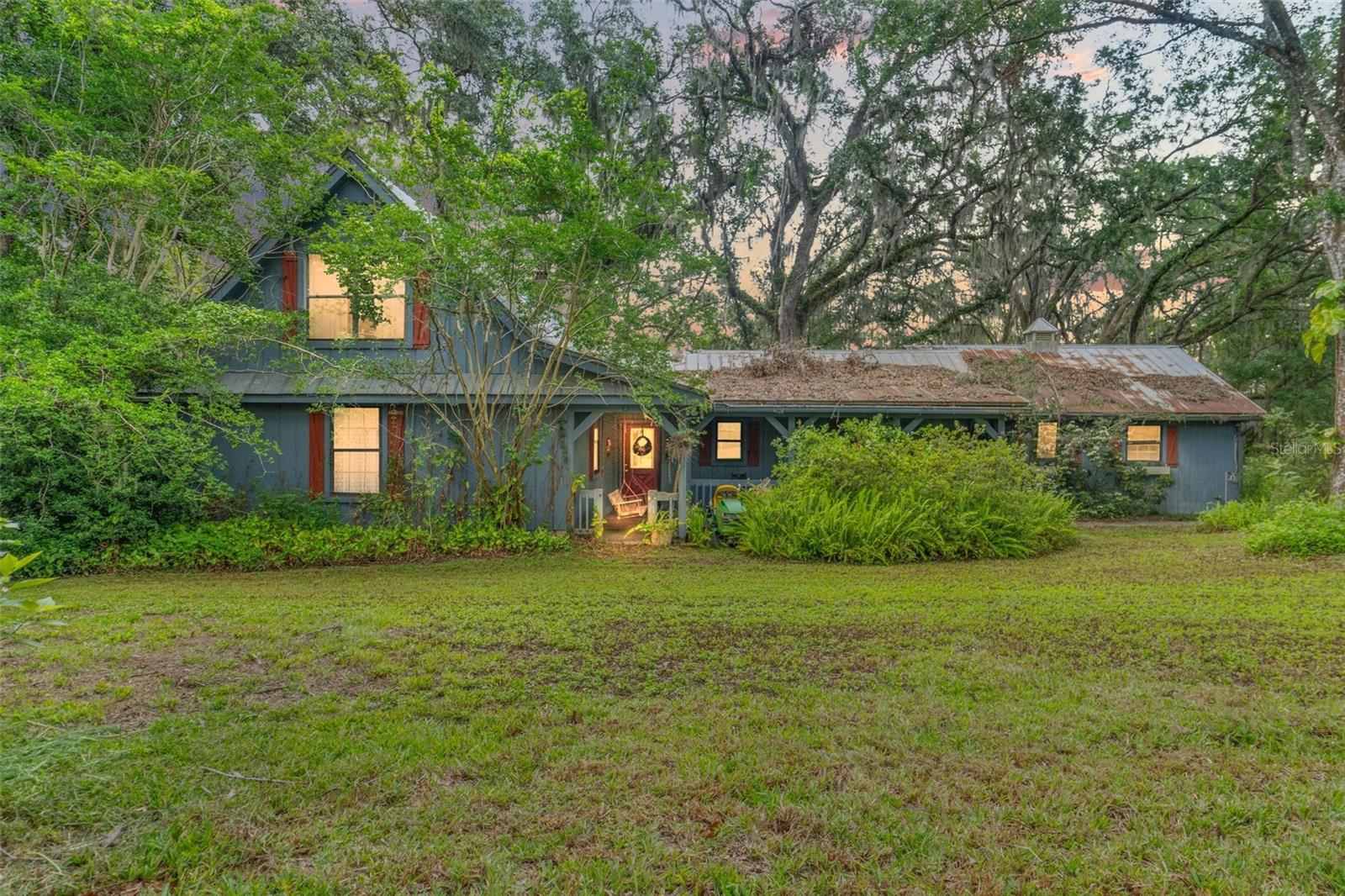 Welcome to 8 acres of untamed enchantment—where winding paths, towering oaks, and the soft rustle of Spanish moss set the tone for a life less ordinary. Nestled at the end of this secluded sanctuary lies a once-beloved 3-bedroom, 3-bathroom cottage spanning 2,183 square feet, yearning for revival and ready to tell its next story.
The home is rich in character, with cathedral ceilings and exposed beams that stretch toward the sky, anchored by a towering brick fireplace that radiates rustic charm. The great room invites light through its dramatic gable windows, and just above, a cozy loft lined with bookshelves offers a quiet perch to dream, write, or reflect.
The kitchen and dining areas echo the warmth of simpler times, and though worn with age, they offer the bones of something timeless. Outside, a weathered metal roof and wooden siding add to the home’s old-soul charm—imperfect, but full of potential for those who see beauty in restoration.
Step beyond the cottage, and your world expands. A sprawling 8-acre parcel surrounds you—peaceful, private, and brimming with natural wonder. Whether you envision a garden, a homestead, or simply a retreat from the world, the land is your canvas. A large storage barn adds practical value and versatility for projects, animals, or creative endeavors.
Yes, this home is in need of serious rehab. But for those with vision, heart, and a love of nature—it’s a rare chance to create something truly magical.