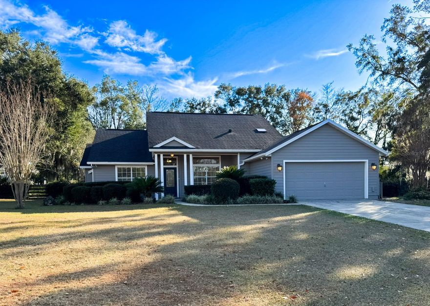 Beautiful 4-bedroom, 3-bathroom home with office/den on just over 1 acre, offering privacy, space, and thoughtful updates throughout. The open floor plan seamlessly connects the kitchen, living room, and dining area, all under high ceilings that enhance the bright, airy feel. The kitchen features real oak cabinets, brand-new quartz countertops, and a brand-new range and refrigerator—perfect for everyday living and entertaining. French doors lead to the back porch, where you’ll find a covered area with two ceiling fans and an additional screened-in porch, giving you multiple options for enjoying the outdoors.   The office/den is a versatile space with custom built-in shelving and a cozy gas fireplace, ideal for working from home or relaxing. The oversized primary suite offers two walk-in closets, a jetted tub, and a walk-in shower, creating a comfortable retreat. All bedrooms and the office/den have brand-new carpeting.  The home has a 2-car garage that includes a water softener and RV hookup. The backyard is fully fenced and offers a large workshop for projects, storage, or additional toys and equipment. This area provides plenty of room to roam and includes olive, peach, banana, and fig trees—adding charm, shade, and seasonal harvests. With mature trees and lots of privacy, this property offers a peaceful setting while still providing all the modern comforts of home. The roof is approximately 5 years old, providing added peace of mind. Additional features include a separate laundry room, irrigation system, and a large walk around attic. This home is located 5 minutes to downtown Alachua and 15 minutes to Gainesville.