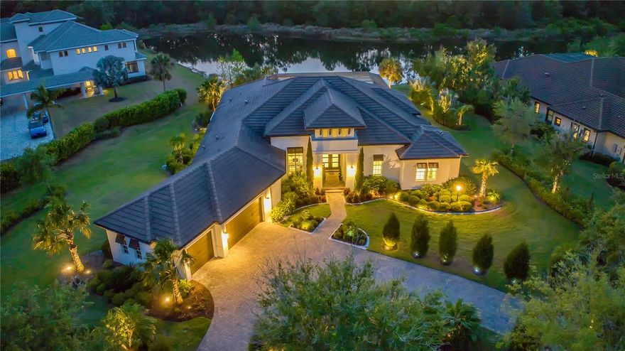 When your favorite destination is home, this impeccable home built by Arthur Rutenberg will welcome you with a fresh expression of luxury and polished design. You are greeted with lush mature landscaping and an oversized circular driveway. The glamorous foyer contains a waterfall chandelier that illuminates a large custom-made wooden framed mirror that spreads the wall. Modern color palette with character-rich finishes. From the moment you arrive, you are mesmerized by the panoramic view of the lake! Stepping into the great room, with a 14' soaring tray ceiling and open-floor plan invite the flow of modern living, a neutral color scheme, and tile floors throughout the home. A crystal fireplace and display alcove with lighting give elegance. Zero-corner 10' impact sliding glass doors create a seamless experience for the lanai. A saltwater pool and spa with sun-shelf and water features are gas heated. The gas fire table, and fully equipped summer kitchen, enhance resort-style living. The panorama screen cage showcases a spectacular view of the lake and picturesque landscaping giving you total privacy. That moment the sunset paints the sky orange and glistens the lake - magic happens. Having a cocktail, reading a book, entertaining....you choose. The gourmet kitchen is a chef's dream. A dynamic 24 pendants stream over an enormous quartz island and countertop. Solid wood soft-close cabinetry with glass display shelves with lighting, touchless kitchen faucet, a 5 burner gas cooktop, coffee, and tea bar with a beverage refrigerator. Entering double doors to the private owner's suite, dramatic floor-to-ceiling glass tile mosaic wall with chandelier connect bedroom, spa-inspired bathroom, and custom-made boutique-inspired closet by California Closet. Space for relaxing and unwinding. The Freestanding 72"x36" soaking tub sits elegantly. Separate quartz vanities with vessel sinks and premium fixtures add a designer's touch. The enormous walk-in shower has 2 shower heads and 1 rain shower head with a built-in quartz bench and shelves. The bonus room is a perfect spot to bring friends and family together for a movie or game night. There are two additional bedrooms and bathrooms for overnight guests; a den, a spacious laundry room with storage space, together with an oversized 3-car garage with shelvings. This home also includes an open cell foam insulated attic, central vacuuming, water softener, and a security system. The indoor AC unit has been replaced including the air handler with 10 year warranty from 9/1/2023.  This is the home for someone who wants to elevate their lifestyle without leaving home! The Concession is Sarasota's most enriched exclusive gated community. High security, no CDD, short drive to dining, shopping, and beaches!