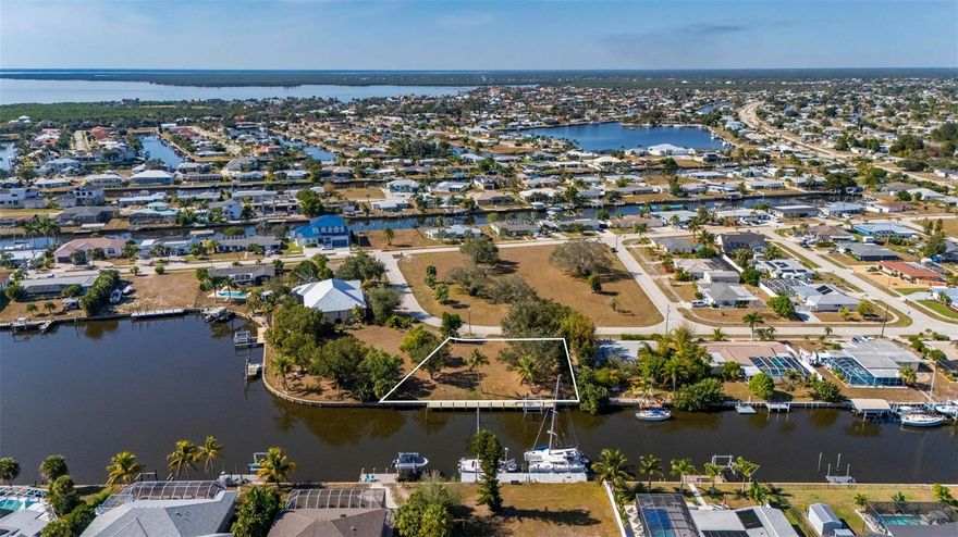 This exceptional .34-acre vacant waterfront lot offers direct sailboat access to the Gulf of Mexico with no bridges, and is ideally located just minutes by boat from the new Sunseeker Resort and downtown Punta Gorda. Directly across from Charlotte County’s Severin Park, the property enjoys a peaceful setting with attractive green space views. The lot measures approximately 95 feet across the front, 138 feet on the right side, 125 feet on the left, and offers 138 feet of waterfront. Extensive improvements have already been completed, including a new seawall cap, hydro-static pressure jet filters, and polyurethane-sealed seams installed by Florida Seawall Solutions in 2022. In 2023, a 97' x 8' marginal dock was constructed along the seawall, with all pilings wrapped in vinyl and cut 60 inches above deck height. The dock features Owens Corning “Barefoot Sands” composite decking, which stays cool even in high temperatures, along with two outer mooring poles. A fully loaded 16,000-lb Deco Concept CRS remote-operated boat lift was also installed, supported by four additional vinyl-wrapped lift pilings. Electric and water service run to the dock and include active 50-amp, 30-amp, and 110-volt outlets, as well as a waterline with backflow preventer. All sewer and water charges are current and paid monthly, allowing the future owner to avoid impact hookup fees when building. With its prime location, high-end improvements, and true sailboat access, this lot is an ideal site for your custom Gulf-access dream home.