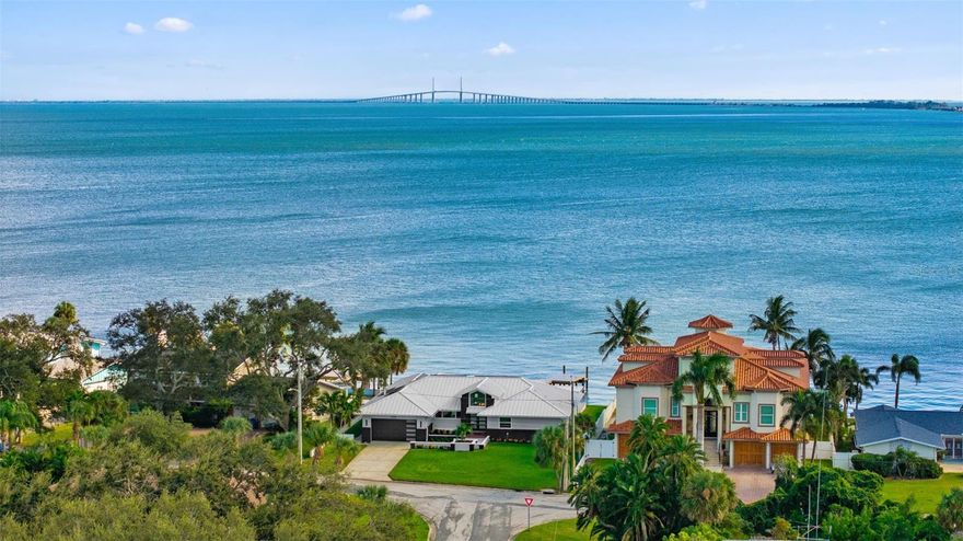Welcome to a truly special waterfront residence with NO HOA, overlooking Tampa Bay and the iconic Sunshine Skyway Bridge. This property not only offers breathtaking views and modern updates but also includes an assumable flood insurance policy at just $3,000 per year—and notably, the home has never flooded, including during the hurricanes of 2024, reflecting its elevated design and superior construction. Perfectly positioned on a .32-acre lot with approximately 90 feet of water frontage, this home captures the best of Florida’s coastal lifestyle—panoramic views, spectacular sunsets, and daily visits from dolphins and sea life right outside your door. From the moment you arrive, the attention to quality and sustainability is clear, showcasing fresh modern exterior paint, brand-new sod and lush landscaping, a standing seam metal roof (2020), new irrigation system (2025), solar panels with battery backups (2022) keeping the average electric bill around $35 per month, and hurricane-impact windows and sliding glass doors (2022) providing peace of mind and protection. The newer seawall & cap, and brand-new marine-grade composite dock extend gracefully into the bay, offering the perfect launch point for boating, fishing, or simply relaxing on the water, with space ready for a boat or jet ski lift if desired. Inside, this 4-bedroom, 2.5-bath home spans 3,062 square feet with a bright, open layout and vaulted ceilings that fill the home with natural light and capture sweeping water views from nearly every room. The layout offers an ideal canvas for personalization—a solid, elevated structure with the opportunity to update finishes to your taste while benefiting from all the major investments already made. The spacious primary suite opens directly to the pool deck and water views, while the additional bedrooms provide flexible space for guests, a home office, or a workout room. Outside, enjoy a sparkling saltwater pool with a gas-heated spillover, surrounded by a brick paver pool deck and large covered lanai perfect for outdoor entertaining. Additional upgrades include a natural gas water heater (2023), dual A/C units with UV filtration, and a new irrigation system (2025).  The expensive heavy lifting is done - move in and make it your own. Ideally located near the Skyway Bridge for quick access to Bradenton and Sarasota, and just a short drive to downtown St. Petersburg, Fort De Soto, and the Gulf beaches, this exceptional property offers the perfect blend of modern efficiency, lasting quality, and breathtaking waterfront living.