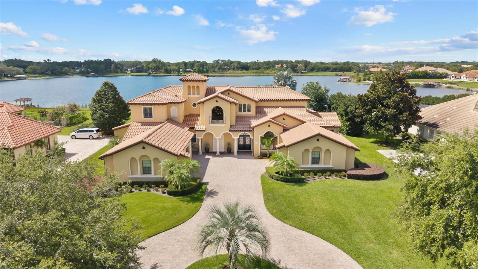 Experience Unmatched Lakeside Luxury in a Custom-Built Masterpiece
Discover the pinnacle of elegance and tranquility in this exquisite custom-built estate, ideally positioned on an expansive lot within an exclusive guard-gated community. With direct access to a crystal-clear spring-fed lake that permits private boat docks, this home offers a rare blend of relaxation, recreation, and refined living.
Step inside to a beautifully designed open-concept living space where the family room and gourmet kitchen seamlessly connect. The kitchen is a chef’s dream, featuring top-of-the-line appliances, a breakfast bar, an inviting eat-in nook, and a spacious butler’s pantry. A custom wine closet nearby provides a perfect display for your finest vintages.
Adjacent to the kitchen, a well-appointed guest suite and a large laundry room enhance the home's convenience. The formal dining and living rooms, centered around a cozy shared fireplace, has stunning views of the lake—creating a warm and relaxed setting for entertaining.
The first floor also features a private office, a full pool bathroom, and a luxurious primary suite. This expansive retreat includes a dedicated exercise room, while the spa-inspired en-suite bath boasts double vanities, dual walk-in closets, a garden tub, and a walk-through shower.
A beautifully crafted wood and iron staircase leads to the second floor, where you'll find two spacious bedrooms, each with its own private bathroom. The expansive game room opens to a lake-view balcony, perfect for taking in serene sunsets. Movie nights are elevated in the state-of-the-art home theater, complemented by a convenient half bath.
Step outside to your own private paradise—an entertainer’s dream. The large covered lanai includes a fireplace and a fully equipped summer kitchen. A sparkling pool and spa, along with a generous open patio, set the stage for unforgettable gatherings or peaceful evenings under the stars—complete with views of the nightly fireworks.
Rounding out this extraordinary residence is a three-car garage, offering ample room for vehicles and recreational equipment.
This is more than a home—it’s a lifestyle. Luxury, privacy, and breathtaking views await. Schedule your private tour today and experience the ultimate in lakeside living. Property can have a boat dock.