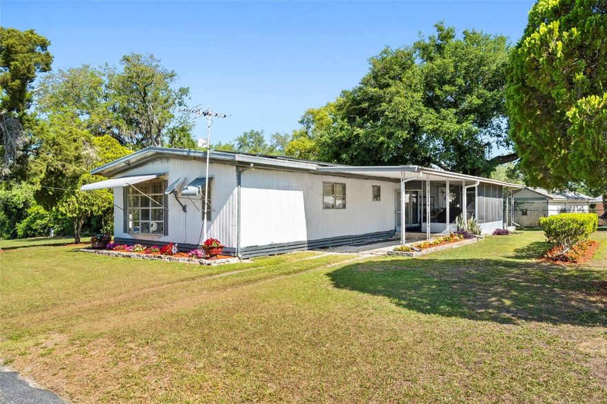 Discover outstanding Florida retirement value in the beautiful town of Dade City at Country Aire Manor | Hampton Court, an age-restricted (55+) community.  This is not a land-lease sale; You own the lot! No big HOA fees, either – just $25 per YEAR membership, plus a monthly maintenance fee ($245) for amenities and water and trash services.  Enjoy the heated pool, clubhouse, pickle ball, planned activities (Bingo! Game Night!), and more.  Golf-cart friendly community. This is an older double-wide mobile home, built in 1973, that needs a little TLC and has been priced accordingly. Home has 3 bedrooms, 2 full bathrooms, inside laundry room, and a 1-car carport with large, screened room and a covered open porch. It features a split floor plan with 1344 cooled square feet of spacious living area. The (central HVAC) air conditioner is newer (4 years old). There is new subflooring/flooring in master bedroom; seller has obtained price quotes for flooring for the remainder of the house. Roof (which is hip/gable and metal) was recently inspected, passed, and now has new solar panels which keep electricity costs down. This may be the prettiest lot in the community and is definitely one of the largest. Lot is 90x100 with a small cutout in back on one side. It is adjacent to community-owned greenspace that owner says soon will be designated as a community park that is dog-friendly. With gardens and open space views from every angle, THIS is truly living the dream. Schedule a tour today.