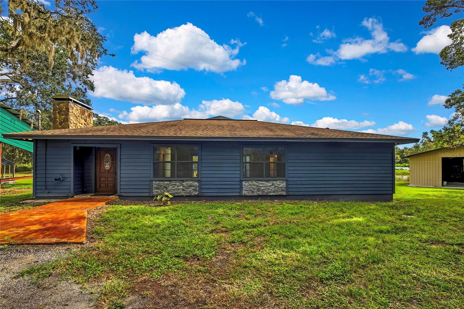 Set against a backdrop of 2.5 acres with a pond view, this Crenshaw Acres home offers 3 bedrooms, 2 baths, and 1,617 square feet of comfortable living space with versatile outdoor amenities. Extensive updates bring peace of mind including Exterior paint 2025! NEW Roof and A/C 2020! Water Heater and Water Softener 2020! Updated Plumbing 2020! Remodeled baths 2020! Zoned for STEINBRENNER School District. The welcoming entry features a Ring doorbell and front door with a glass insert. Inside, the family room showcases engineered hardwood floors and a modern stacked-stone wood-burning fireplace flanked by sidelights, along with a closet and two sets of double sliding glass doors leading to the lanai.
The kitchen remodeled in 2020 includes cabinetry with a Quartz counter, tile backsplash, a farmhouse sink beneath a window overlooking the backyard, a closet pantry, and an island with cooktop and lighted vent hood. A breakfast bar provides ample seating and opens to the family room. Off the kitchen, the laundry room comes equipped with washer and dryer plus direct backyard access. The master suite features engineered hardwood flooring, a walk-in closet, and an ensuite bath with a glass-enclosed tiled shower, double-sink vanity, and skylight. Secondary bedrooms are well-sized with closets and share a full bath with a vanity and tub/shower combo with glass enclosure. A split-bedroom floor plan ensures privacy. A hallway with sliding glass doors opens to a spacious screened deck at the center of the home—perfect for gatherings with family and friends. This area also includes a storage room with an access door to an additional deck with steps down to the expansive backyard, where deer and other wildlife can often be seen. Outdoor living is further enhanced by a detached garage (approx. 24x32) with concrete floor, a 14x36 RV carport, open parking, and a chicken coop. The treed area in back, adds natural charm in a parklike setting alongside peaceful pond views. Crenshaw Lake Road provides a tranquil residential setting with proximity to major thoroughfares including US-41, SR-597, and I-275—ideal for quick travel into Tampa or surrounding areas. Shopping, dining, schools, parks, and medical facilities are all within easy reach, offering both convenience and serenity. Don’t miss your chance to own this unique Lutz property—schedule your private showing today!