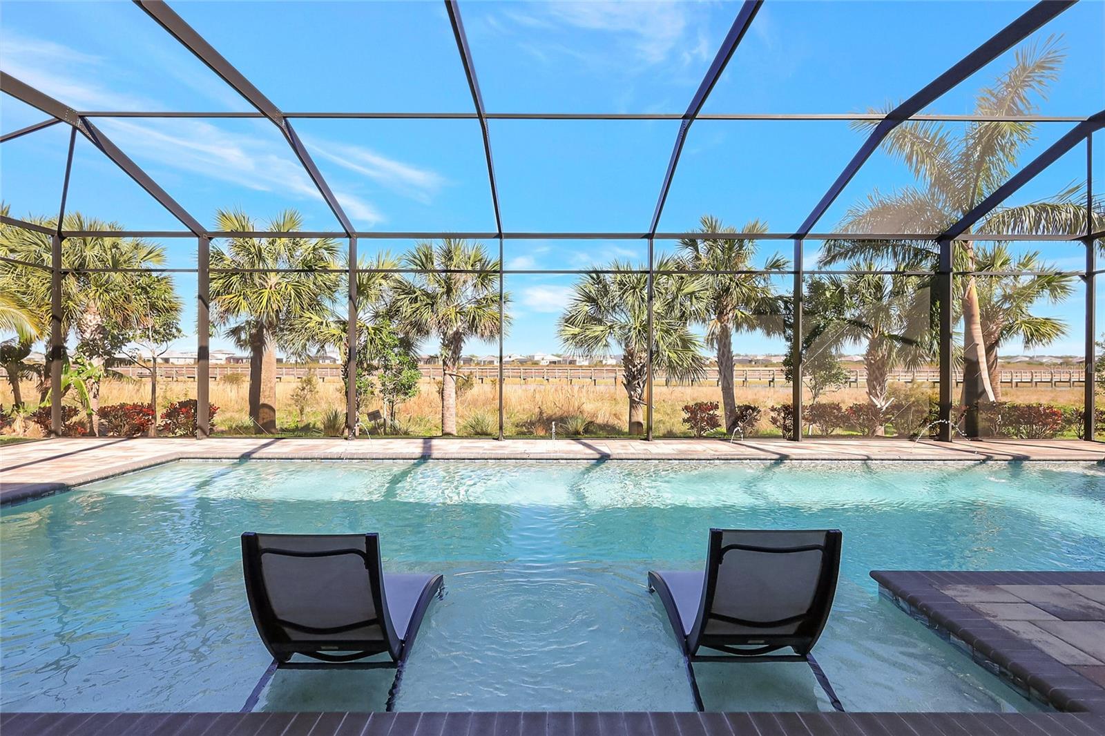 Elegance and refinement are surely an understatement in this stunning San Giorgio Model, perfectly positioned overlooking a vast preserve in the highly sought after community of The Isles in Lakewood Ranch. Experience both luxury and functionality in this magnificent Open Floor plan that will definitely impress you from the moment you walk in thru the custom glass doors, you will appreciate all the delicate, yet beautiful details of this home, beginning with the 15-foot high ceilings, the Luxury Vinyl wood like plank flooring, impact resistant windows and doors thru out, sophisticated lighting thru to the openness of the floor plan. The great room provides high ceilings with double trays and impressive 90-degree glass sliding doors to the spacious pool area and nature views at its' best. The fabulous gourmet kitchen with its two-tone cabinetry, vast island with extra lower cabinets, under cabinet lighting, walk-in pantry, quartzite counter tops, soft close drawers, Kitchenaid top of the line Stainless Steel Appliances, glass backsplash, wine fridges, just to name few of the upgrades. Adjacent is the formal dining room all of this opening to the incredible outdoor area to be able to fully enjoy our Sunshine State, leading with a magnificent salt water lap pool with gas heater, sun shelf, paver, outdoor kitchen and powder room accessible from lanai. The spacious owner’s retreat boasts tray ceilings, a peaceful sitting area, two substantial walk-in California styled closets, ensuite master-bath with dual vanities, garden tub to relax after a long day and separate shower stall. Two additional bedrooms, one with a lovely ensuite bathroom, plus an office/den. Large laundry room with extra cabinets, granite counter tops and folding area. Total of three-car garage with epoxy floors. This gated community has great amenities such as Pier House complete with kitchen, indoor/outdoor fireplace, outdoor seating with TV’s, Resort Style pool, lap pool, yoga studio, gym, two doggie parks, ½ basketball court, playground, tennis courts, pickle-ball courts, raised boardwalk through wetland preserve. All within minutes of UTC Mall, Lakewood Ranch Main Street, Polo fields, Benderson Park, golf courses, great dinning, shopping, arts, theaters, rated A schools, close to Sarasota, International Airports, Tampa, St-Pete, Naples and of course our world renown beaches on the Gulf