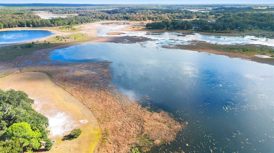 Your Wild Florida Dream Awaits – 1.33 Acres of Waterfront Freedom (Zoned A1).  Escape the city, silence the notifications, and let the squirrels be your new HOA. Tucked away in the southern stretch of the Ocala National Forest, this 1.33-acre waterfront lot is the perfect place to build, plant, camp, glamp, fish, dream, or simply hide from your responsibilities (we won’t tell). With A1 zoning, this land gives your imagination full permission to run barefoot and free. Build your dream home. Place a manufactured home. Start a glamping empire. Grow a garden big enough to finally impress your in-laws. Or—if you’ve been waiting for a sign—this might just be the moment to create that tiny-home AirBnB village you’ve been doodling on napkins for years. Nestled right around the Big Bass Campground, you’ll be in good company with nature lovers, fishing fanatics, and hunters who know how to swap stories around a campfire. Or keep the land entirely for yourself and build the log cabin of your dreams complete with deer heads, singing bass plaques, and taxidermy. The property has been cleared and already equipped with well (operability unknown, but hey, that’s part of the adventure), the hard stuff is already started, just bring your ideas and maybe a toolbox to build a dock and spend your days fishing with a koozie in hand. This land has been in the owner’s family for many, many years, holding countless memories and meaning. Now, it’s ready for a new chapter with you and your future generations.  Come write your story on this peaceful, private, beautifully wild slice of Florida. Opportunities like this don’t come around often… but when they do, they usually involve a lake, some trees, and a whole lot of potential.