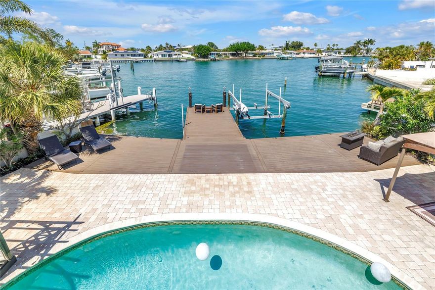 There are homes that check boxes… and then there are homes that create a feeling the moment you arrive.

Tucked behind swaying palms and a private courtyard, this Spanish Mediterranean waterfront residence unfolds with warmth, character, and architectural drama. Steeped in local lore, this Belle Vista waterfront estate is said to have once hosted lavish gatherings under the ownership of a British noble. Step inside and you’re immediately drawn to a sweeping spiral staircase wrapped in wrought iron—a true centerpiece that sets the tone for the entire home.  

Arched openings, soft textures, and curated finishes create a sense of timeless elegance, while thoughtful renovations and modern systems bring effortless living to every space. Designed for both everyday living and unforgettable entertaining, the home offers five bedrooms, including two primary suites—one on each level—ideal for guests or multi-generational living.  And a grand fireplace in the formal living room that cant help but grab attention!

At the heart of the home, the kitchen is both striking and functional—featuring a Monogram professional refrigerator, GE Café six-burner gas range, convection oven, warming drawer, and Bosch dishwasher, all complemented by custom cabinetry, Brazilian granite surfaces, and integrated wine refrigeration. Just beyond, a custom-built entertaining bar and piano room overlooking the water set the stage for evenings filled with music, conversation, and light dancing across the bay.

Upstairs, the reimagined primary suite becomes a true retreat, opening to a wraparound balcony with new cable railing—perfect for morning coffee or sunset views with wine in hand. The spa-inspired bath offers a freestanding soaking tub, multi-head custom shower, and refined finishes designed for relaxation.

Throughout the home, designer lighting, updated flooring, and smart home integration seamlessly control lighting, pool, spa, and security—blending convenience with elevated design.

Outside, the experience continues. Expansive multi-level decking overlooks the water, leading to a resort-style pool and waterfall spa, fully automated and enhanced by ambient lighting. A spiral staircase rises to an elevated terrace, offering sweeping views of the surrounding waterways and tropical landscape.

For boating enthusiasts, deep water access, a private dock with 12,000 lb lift, and quick passage to Boca Ciega Bay and the Gulf of Mexico make this location as functional as it is beautiful.

Significant upgrades—including a new Eagle tile roof, propane system servicing the gas range and spa heater, updated water heaters, and enhanced pool systems—provide peace of mind behind the beauty.

As evening falls, landscape and underwater lighting transform the setting into something truly magical—private, peaceful, and quietly spectacular.

This is more than a home. It’s a place to gather, to retreat, and to live beautifully by the water.