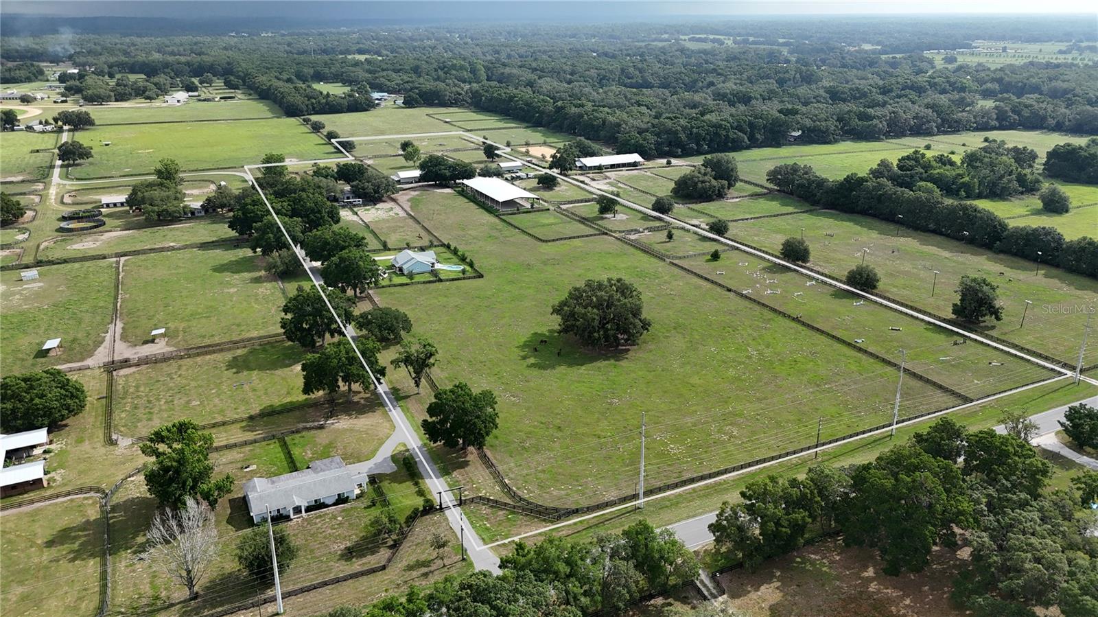 Oaks Lane gated equestrian property on approximately 25+/- acres.
Enter through the gated entrance to the 3-bedroom, 2-bath residence with a split open floor plan. The living room features a large center fireplace with modern lighting, providing the perfect ambiance for entertaining family or guests or setting the mood after a long work day—a chef's kitchen with custom cabinets and granite countertops. The owner's suite offers a luxurious bath and a spacious closet. The back screened in lanai and an outdoor heated saltwater pool. A fenced dog yard, a whole house generator, and a 500-gallon propane tank enhance the property.
Equestrian facilities include an 80' x 200' covered, lighted arena with fiber and sand footing, a sprinkler system, and 2 large fans.
A 16-stall center aisle barn with TheraPlate, a half bath, an air-conditioned tack room, an enclosed feed area, and 2 wash racks.
The multipurpose building offers seven stalls with automatic waters and fans in each stall, two apartments (2/1 and 1/1), a laundry and storage area, and open space for equipment or parking your horse trailer, plus 15 lush green paddocks with 4-board fencing. The large paddock is level and flat and is currently used as a jump field.
There is a 30' x 48' equipment building with concrete flooring. The property has two interconnected wells.
It is conveniently located near the Florida Greenways and Trails, the Florida Horse Park, and just 20 miles from the World Equestrian Center.
