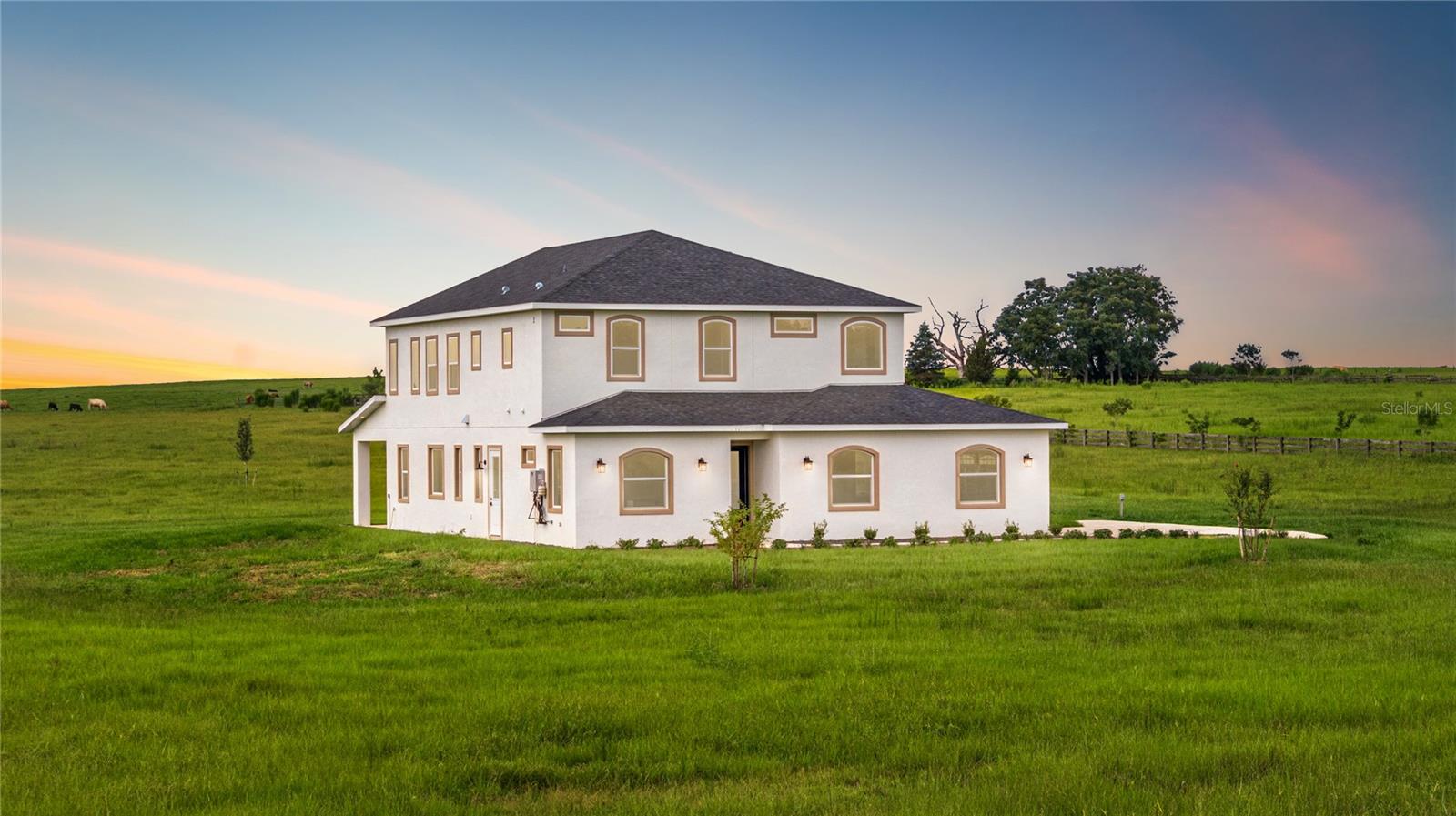 Welcome to this newly constructed Two-Story Custom-Built Estate nestled on 11 manicured acres of gently rolling pasture land (high & dry). This one-of-a-kind exquisite home spanning 4,599 total square footage harmonizes comfort, splendor, and serene countryside living—all while being just 30 minutes from Ocala and the World Equestrian Center, 35 minutes to Crystal River, and 45 minutes to Gainesville. Enjoy renowned natural attractions such as Rainbow Springs, Devil’s Den, and Cedar Lakes—all within 25 minutes of your doorstep. This 4 Bed/4 Bath rare masterpiece showcases an open-concept design, soaring ceilings, energy-efficient double-pane windows, and natural light pouring in from every direction—capturing breathtaking sunrises, sunsets, and panoramic views of grazing farmland. The Lower Level boasts 2,679 total sq.ft. featuring; a side-load 4-car garage, executive office (or optional 4th bedroom), guest bathroom, formal living room/dining room combo, private gym room, and covered lanai for year-round outdoor enjoyment. The gourmet kitchen is designed for the culinary enthusiast with custom cabinetry, gas range, and Quartz prep island. The walk-in pantry and laundry room combo includes a built-in pet bath station and laundry chute from the second floor. The Upper Level offers 1,920 total sq.ft. A stairway ascends from the kitchen to the en-suite bedrooms, and a large bonus/flex room. The owner’s suite offers a spa-inspired bath, separate vanities, walk-in closet, and scenic acreage vistas for the perfect personal retreat. French doors open to a balcony, offering sweeping views of the property. Beyond the enticing features, endless opportunities lie just beyond your front door. The property’s A-1 zoning allows for barns, accessory buildings, livestock, equestrian facilities, and a variety of agricultural uses—ideal for creating a horse farm, cattle operation, or your own private sanctuary. Your countryside paradise awaits! NO HOA, NO Flood Zone!