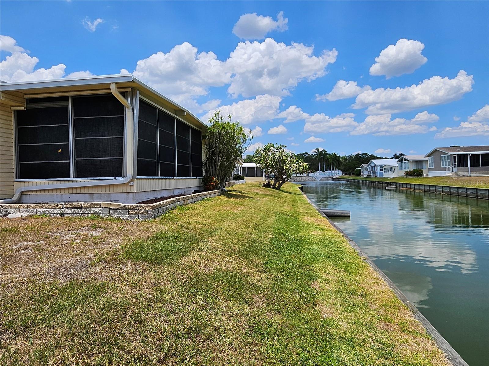 Great Price for Waterfront home located in the ONLY Resident Owned Park in the City limits of Sarasota!!
This 2 bed 2 bath gem is waiting for you to put your personal touch on it. The kitchen has tile flooring, a decorative tile backsplash, updated cabinets and counters giving plenty of storage and counter space, 2 pantries, a flat top stove and a dishwasher have been added. Just off the kitchen is a space suitable for a breakfast table or desk/work area. The living room is accessible from the kitchen and has sliders leading to the lanai where you can enjoy views of the sunrise overlooking the water. The lanai also has access to the carport and a convenience ramp, 2 ceiling fans, a wall unit AC ( not sure if functioning) and newer hurricane shutters. The formal dining space is accessible from the kitchen and living room. The primary suite has a roll top desk, walk in closet and an updated en suite bath with step in shower additional storage closet and a built in safe. The guest bedroom has a double bed, dresser walk in closet and is just across from the full size bath with a shower/tub with tiled walls and high vanity. The storage shed houses the washer, dryer, utility sink, water heater, and has been enlarged to 190sf providing ample space for storage. Home is partially furnished, both bedrooms have escape doors. Home is partially furnished. Oakwood is a 55+ / no pet / no motorcycle park.
Original updates include: Kitchen, Baths, AMS roof over 2000, carport elastomeric RO, HVAC 2014 3ton with 2 UV lights, water heater 2017 38gal housed in shed, vinyl windows on lanai 2001 and newer hurricane shutters for lanai, windows on home updated 2001 single pane, vapor barrier 2010, 10 tiedowns added 2010, plumbing is pvc and copper with shutoffs, sewer line 2010, sub panel in shed is updated Sq D, built in large safe,
The gated 90 acre community boast low maintenance fee with its vast amenities starting with the large Clubhouse outfitted with a full commercial cook kitchen, event stage, audio/visual, dance floor, fitness room, activities hall, library with books/movies/puzzles and a pool table. Outside recreation includes an extra large heated pool with a handicap ramp, a spacious kidney shaped hot tub, ample tables and lounge chairs and remodeled shower rooms. Oak trees shade the beautiful park area, picnic tables and a community grill. Additional amenities to enjoy are the community putt putt course, bocce ball, ping pong, horse shoes and corn hole. Oakwood Manor is a highly social community with many groups and activities to be a part of. We are located adjacent to Legacy Trail and 12 new pickle ball courts managed by the City. Close to downtown, shopping and dining. Please note that Oakwood is a NO pet and NO motorcycle Park.