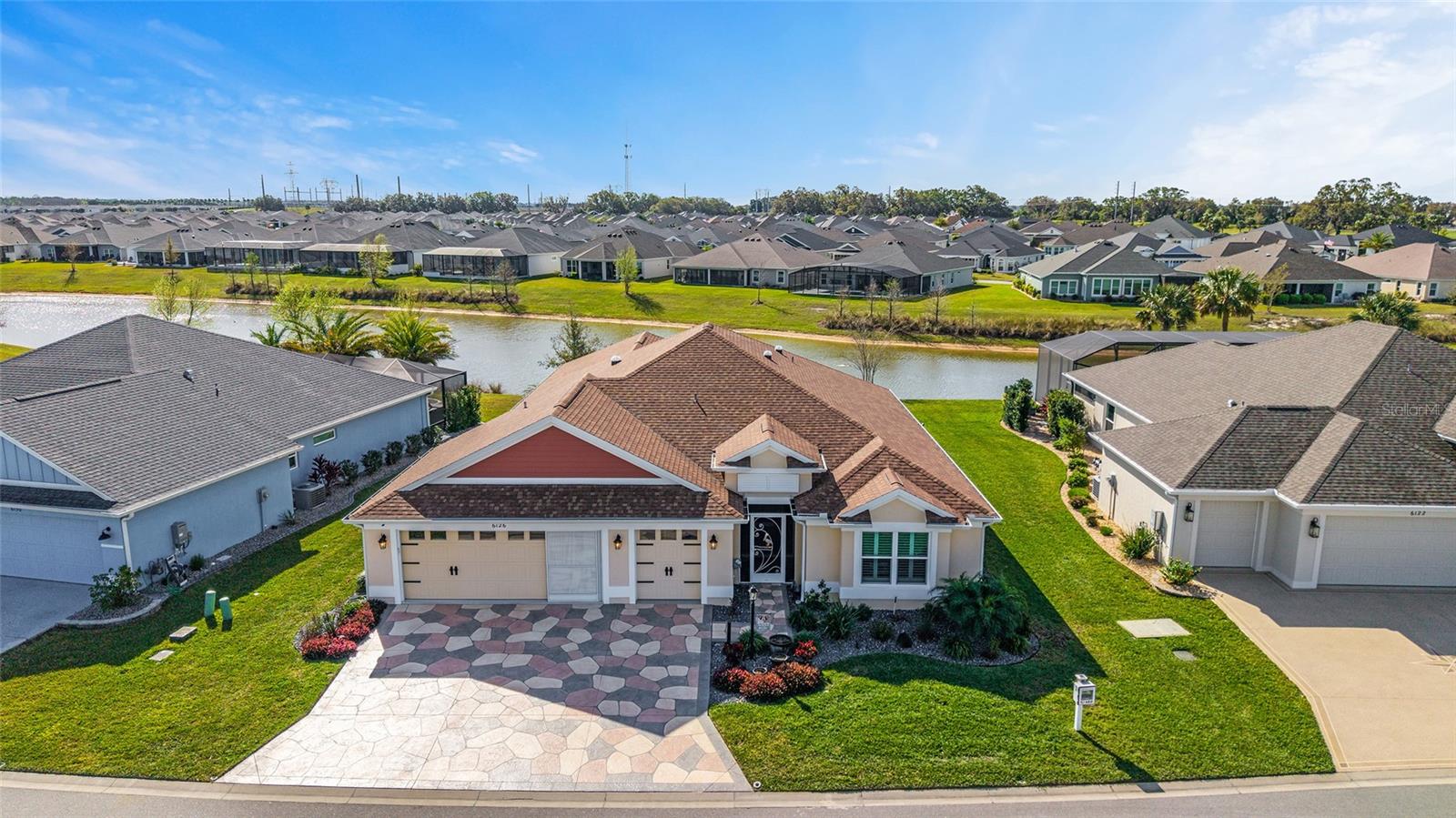 Waterfront Designer Iris (room for a pool) home built in 2021 like no other, located in The Villages of Southern Oaks, with an astonishing 2,930 living square feet and a splendid view of the lake and room for a pool. Buckle up, because everything coming next is mind-blowing. An additional 872 square feet of open floor space was added to the rear of the house with oversized glass windows giving wonderful panoramic views of the lake, including roller shades to keep the sun off - you can see out, but others cannot see in. The space also features three mini splits and raised floors to eliminate any step-downs. An elegantly laid-out flagstone patio with lighting is available if you care to venture outside for fresh air. The kitchen is a chef's dream come true, with two full-sized double ovens, a gas stove, ample quartz countertops, a backsplash, stainless steel appliances, barstool seating, endless sparkling white cabinets with pull-out drawers, and a breakfast nook. The primary bedroom is simply majestic, with everything jumbo-sized, from the closet to the walk-in shower, dual sinks with plenty of drawers and counter space. The home features sealed porcelain tile flooring, plantation shutters, crown molding throughout, a tankless water heater, shiplap on two accent walls, a queen-size Murphy bed that transitions into a desk in one of the spare bedrooms, custom closets in the master closet and garage, security cameras, a whole-home surge protector, 4 solar tubes, and keyless entry at the front door. Even the garage has a mini-split, extra insulation, plywood flooring in the attic, and magic stairs with a lift to get all your belongings up safely. Absolutely unequivocally, one of the most pristine homes in all of The Villages awaits you. Call today to schedule your very own private showing.