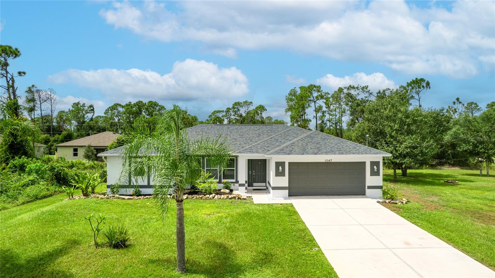One or more photo(s) has been virtually staged. Set on a rare .51-acre corner lot, this updated 3 bedroom, 2 bathroom home offers just over 1,700 sq ft of move-in ready living with plenty of space to enjoy inside and out. The oversized lot provides privacy, mature oak trees, and fruit trees including peach, banana, and strawberry guava, along with a Moringa tree, all supported by an updated irrigation system with new sprinkler heads. Inside, cathedral and tray ceilings, fresh baseboards, and abundant natural light highlight the thoughtfully designed split floor plan. The central kitchen features refreshed cabinetry, counters, and a pantry, opening seamlessly to both the living and family rooms. The private primary suite includes dual closets, one a walk-in with built-in shelving, and a remodeled ensuite bath with a beautifully tiled walk-in shower. Two additional bedrooms also offer walk-in closets, and the second bathroom has been updated with modern finishes. French doors in multiple rooms lead to an expansive screened lanai with concrete columns and ceiling fans, creating a perfect retreat for year-round outdoor living. Additional features include porcelain tile flooring, a laundry room, ceiling fans in every room, and a large two-car garage complete with a workbench, wall-mounted TV, and steel storage racks. Major improvements include a new roof in 2023 and a new AC in 2022, giving added peace of mind. Conveniently located near schools, shopping, dining, Myakkahatchee Environmental Park, the North Port Aquatic Center, Charlotte Sports Park, and a short drive to Gulf beaches. **THIS PROPERTY QUALIFIES FOR A 1% LENDER INCENTIVE IF USING PREFERRED LENDER. INQUIRE FOR MORE DETAILS.**