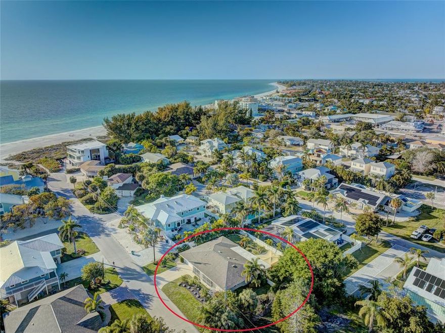 One or more photo(s) has been virtually staged. Imagine stepping out of your front door and only being FIVE houses away from Holmes Beach on Anna Maria Island!!  This 3 bedroom, 2 1/2 bath, split floor plan home will not last!  The light and bright open living space has stunning terrazzo floors, recessed lighting throughout, and plenty of room for entertaining and family gatherings with multiple sitting and dining areas.  Designed with storage in mind and remodeled in 2013, the modern kitchen features stainless steel appliances, quartz countertops, and custom white cabinetry.  The owner's suite has a large walk-in closet, many windows, and an en suite bath with a huge handicapped accessible tile shower. The two guest rooms have large closets, ceiling fans and one features a built-in window seat and carpet.  Completing this home are two tiled Florida rooms that lead out to the paver patio and vinyl deck, with a removable sun shade, at the back of the house.  The property is surrounded by white vinyl fencing for privacy.  After a walk back from the beach, wash off the sugar-white sand in the outdoor shower.  There is a large 2 car garage with a half-bath.  Enjoy entertaining in the outdoor oasis with gorgeous landscaping, an outdoor sink, and floodlights on the back of the house.  For peace of mind, the AC was replaced in 2019 and the water heater was replaced in 2022.  The private location of this home has no through traffic or street parking.  Enjoy all that island living on Anna Maria has to offer with breathtaking views, exquisite white sand beaches, and charming old Florida local culture.