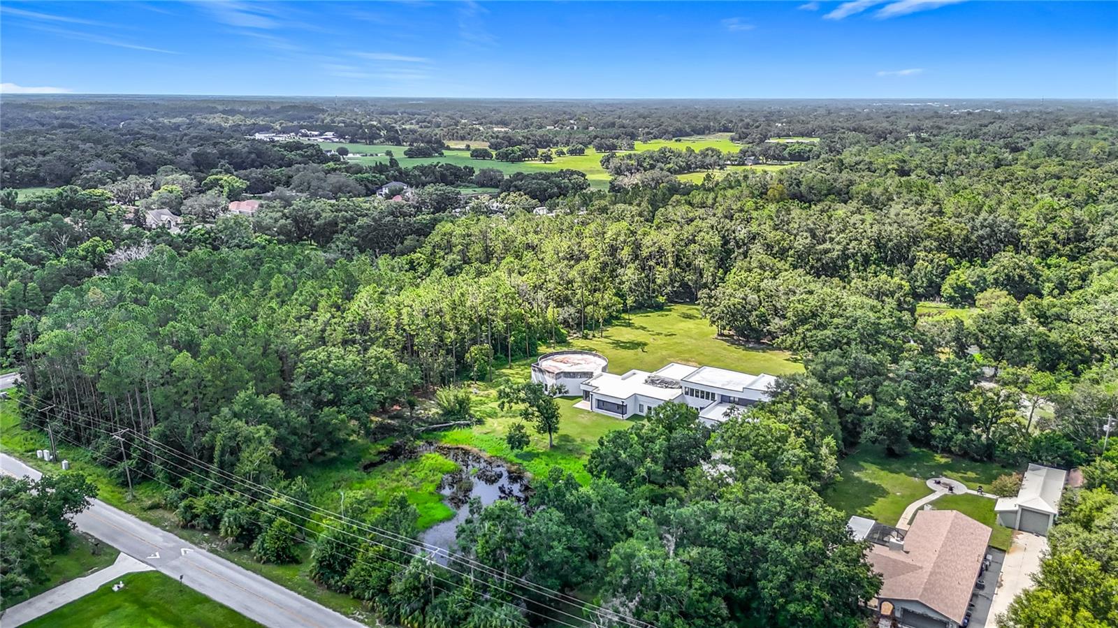 Modern Luxury Estate with Instant Equity – 2518 Sunset Lane, Lutz, FL 33559. Discover a rare opportunity to own an ultra-modern luxury estate offering immediate equity and boundless potential in the heart of Lutz. Nestled on over 4 private acres, this architectural masterpiece spans more than 8,000 sq ft and was recently appraised at $3M as-is and $3.5M when completed, offering $300K in instant equity with the potential to exceed $800K+ once fully customized. Boasting 6 bedrooms and 6 bathrooms, with the option to expand to 8 beds and 7+ baths, this estate features a massive chef’s kitchen with dual 4’x10’ quartz waterfall islands, commercial-grade appliances, and custom cabinetry. The floor-to-ceiling glass living room overlooks twin private ponds, while smart wiring throughout supports automated shades, invisible speakers, whole-home audio, and a 30-camera surveillance system. Entertainment options abound with a wired movie theater and game room, and rooftop decks and balconies provide panoramic views, awaiting final railings. A hidden studio office can easily convert to a second master suite with its own private bath. Elegant finishes include matching wood-look porcelain tile, subway tile accents, rock splash flooring, and black stainless fixtures. The property also features custom commercial-grade water filtration and septic systems, two Generac commercial-grade generators with automatic transfer switches, and a self-contained 1,000+ gallon propane tank for energy efficiency. This home is 90% complete and fully livable, with most finishing materials already on-site. Included blueprints, contractor connections, and a full materials package make it easy to personalize the final details. All of this is just minutes from Tampa’s major highways, luxury amenities, and vibrant city life, while offering serene privacy on a secluded estate. Don’t miss this once-in-a-lifetime chance to own a modern sanctuary with unmatched value and prestige — schedule your private tour today.