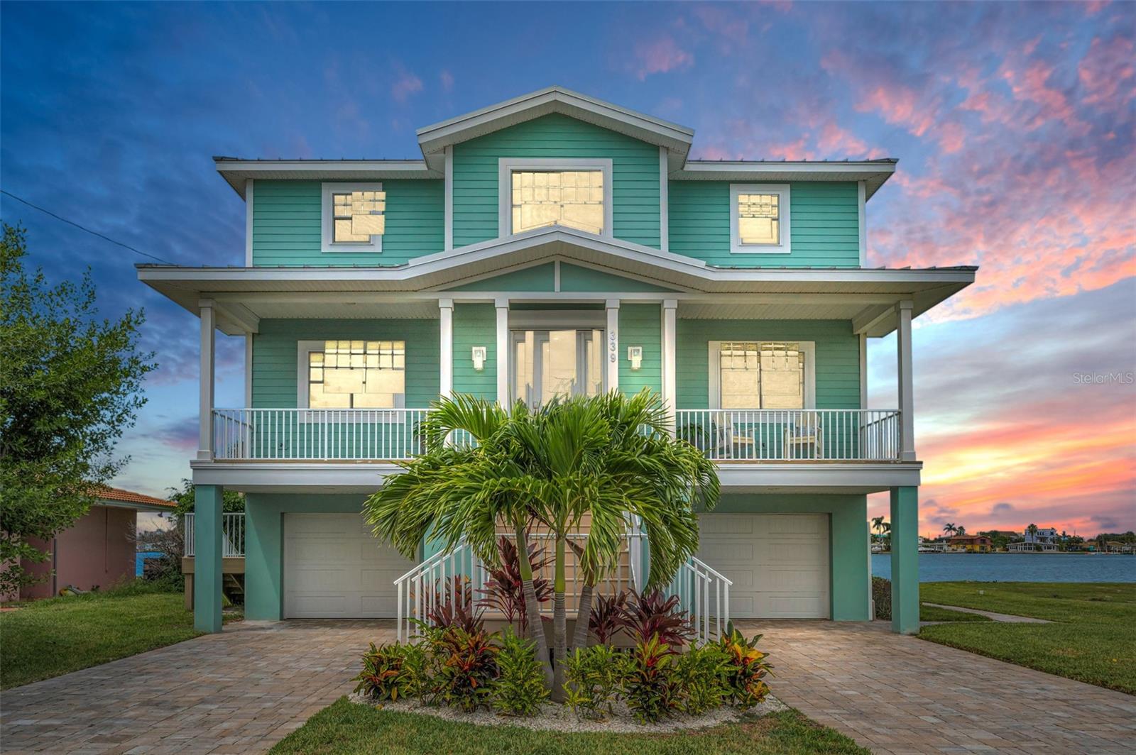 THE BEST OF BOATING AND THE BEACH, THIS BEAUTIFUL 5 BEDROOM, 4 BATH COASTAL CONTEMPORARY RESIDENCE FEATURES RARE FRONT AND REAR (NORTH AND SOUTH) WATERVIEWS! Feel the immediate coastal living vibe with your first step on the property of this home, an experience that will never grow old. A dual entry brick paver driveway introduces a covered front porch with two separate sitting areas overlooking the waterfront. Beyond the pleasing entry foyer, discover a home that feels virtually brand new! Elegant wood flooring and rich detailed finishes provide a deeply satisfying living appeal. Enjoy sweeping water views from the expansive great room and dining area. The living room integrates an entertainment wall/LED fireplace with shiplap wall finishes. Step out to the 39ft-wide covered deck and take-in dazzling panoramic views of the water; the huge deck presents three distinct sitting areas and offers access to the lower level. Your designer chef’s kitchen will make your culinary experience a true joy - with exquisite quartz surfaces, exceptional shaker-style coastal cabinetry, high-quality stainless-steel appliances, lovely tile backsplash, pantry, a terrific island prep center with breakfast bar, and excellent waterviews. Both of the first living level bedrooms are sizable and have their own waterviews, with bedroom one opening to the covered balcony. The lavish full guest bath contains a rich quartz vanity, travertine tilework throughout, and a fabulous walk-in glass shower enclosure. Your impressive upper level holds three spacious waterfront bedroom suites. The superb owner’s suite includes a generously-sized walk-in closet with closet system, and private access to an inspiring 300sqft+ covered balcony with commanding views of the waterfront. The gorgeous owner’s bath is luxurious, boasts two large/separate quartz vanities, a plush soaking tub encased in resplendent tilework, a sumptuous walk-in glass shower enclosure with two shower heads, and lovely water views. The 2nd and 3rd bedrooms suites are large and beautiful, with graceful full baths (suite 2 opens to the upper-level balcony). The lower level has two oversized garage spaces, and a large multi-purpose area ideal for fitness, gaming or storage. The 300sqft covered lower-level deck overlooks the back yard and waterfront and is perfect for lounging and relaxing after a boating or beach day. The updated seawall and composite dock with runway lighting have a step-down area for kayak/paddleboard launching. Dock supports a 13,000lb lift - from here you’re an easy 10-minute board ride to the Gulf! Water filtration/softening system, epoxy garage flooring, posh finished 3-stop elevator and so much more. An outstanding value in a truly uncommon location where all homes are on the water! Just a 3-minute walk to the pristine soft white sands of TripAdvisors #1 rate beach, and a 5-minute walk to dining, shopping, entertainment! All dimensions are estimates, buyer to verify.
