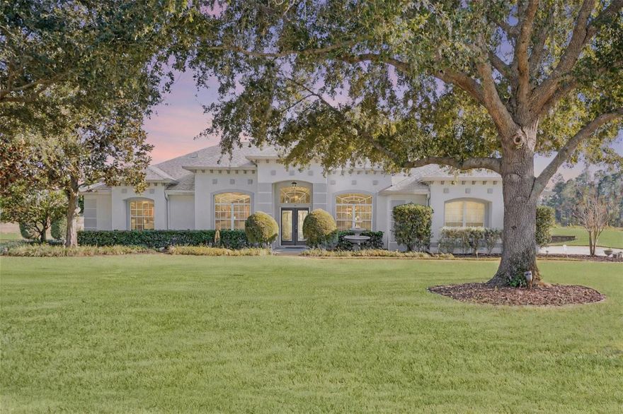 Beautiful and meticulously maintained, this stunning 4 bedroom, 3 bath pool home sits on over 1 acre in the highly desired Arrowtree Reserve. This spacious tri-split floor plan features a screened pool, outdoor kitchen, and gorgeous waterfront views that create the perfect indoor/outdoor lifestyle. As you enter, you’re greeted by a formal dining room and dedicated office/den, flowing into a bright kitchen with quartz countertops, and views into the family room. Brazilian hardwood floors run through the main living areas, complemented by beautiful wood ceiling beams, fireplace, and thoughtful details throughout. The large primary suite offers peaceful pool and water views, a spa-like bathroom with dual vanities, fireplace, a soaking tub, a large walk-in shower, and an expansive custom closet with built-in organizers. The 4th bedroom functions as an ideal guest or in-law suite with its own full ensuite and convenient pool bath. Outside, enjoy sunrise over the water from the pergola, or relax under the spacious screened lanai. Additional highlights include an oversized side-entry 3-car garage, tons of storage, a newer roof (2020), AC (2018), heat pump (2021), and a beautifully maintained 1+ acre lot. Located just minutes from Hwy 19 and the turnpike, this home checks all the boxes for comfort, beauty, and convenience. *Aerial photo property lines are an estimate and to be verified by buyer.