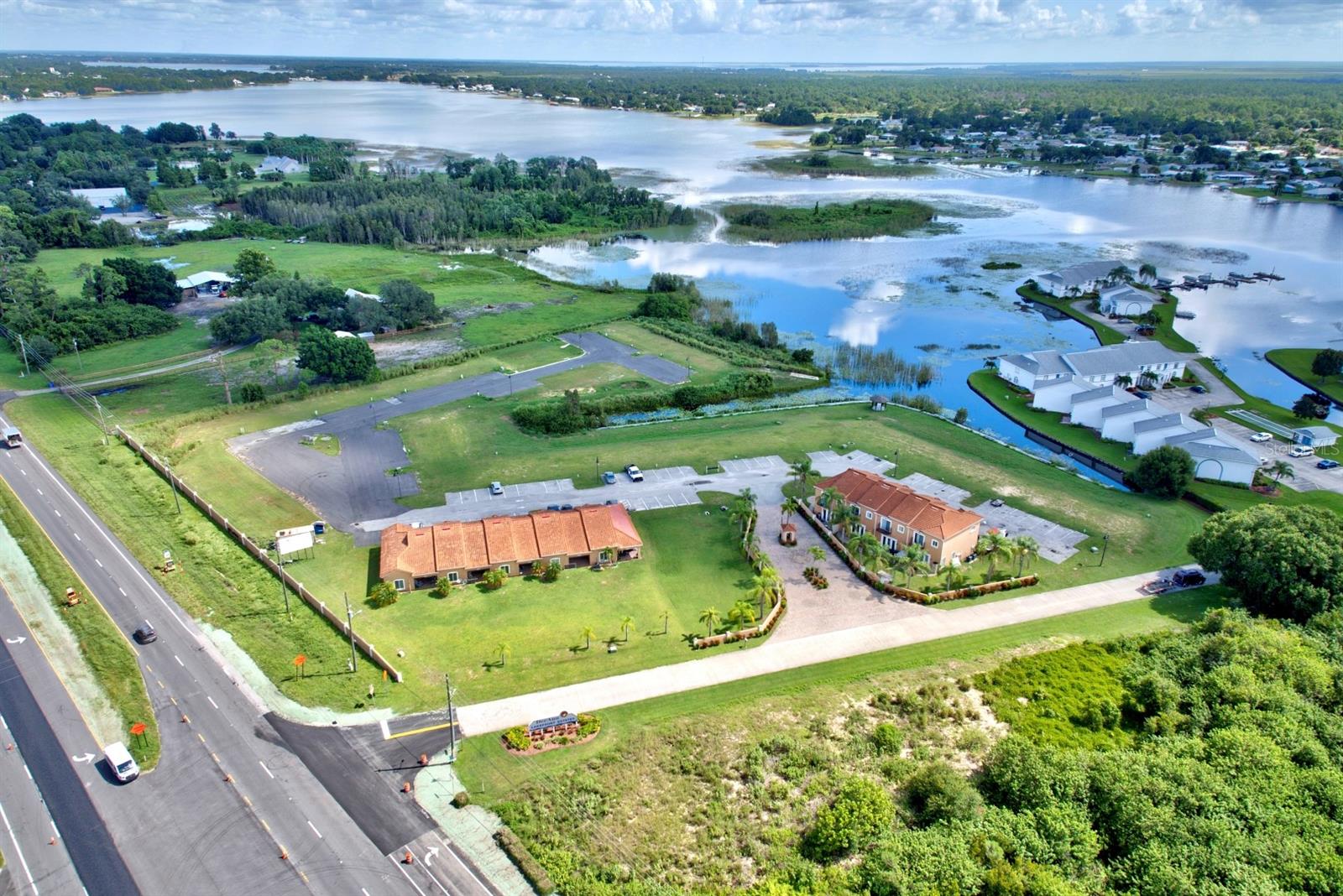 Located along Highway 27, this 6.03-acre property has waterfrontage on Lake Grassy. It offers significant development potential with existing infrastructure in place for residential expansion. The property includes a 9-unit complex: five single-story units (2 beds, 2 baths, approximately 1,540 sq. ft. living space) and four two-story units (3 beds, 2.5 baths, about 1,534 sq. ft. living space). Completed in 2008, Phase 1 is finished. Phase 2 proposes constructing 42 additional 3-bedroom, 2.5-bath units, each about 1,565 sq. ft. of living space. The design and the size of units can be modified to meet your needs. All necessary infrastructure, including paved roads and utilities, is ready, making this a shovel-ready project. Proposed plans for the new units are included, along with a wastewater management permit valid through 2029. The site also provides space designated for a community pool. This property provides a fully prepared development site with existing income units, without zoning changes or significant infrastructure costs. Its highway frontage, water access, and ready-to-build status make it an attractive option for developers or investors seeking immediate development potential.