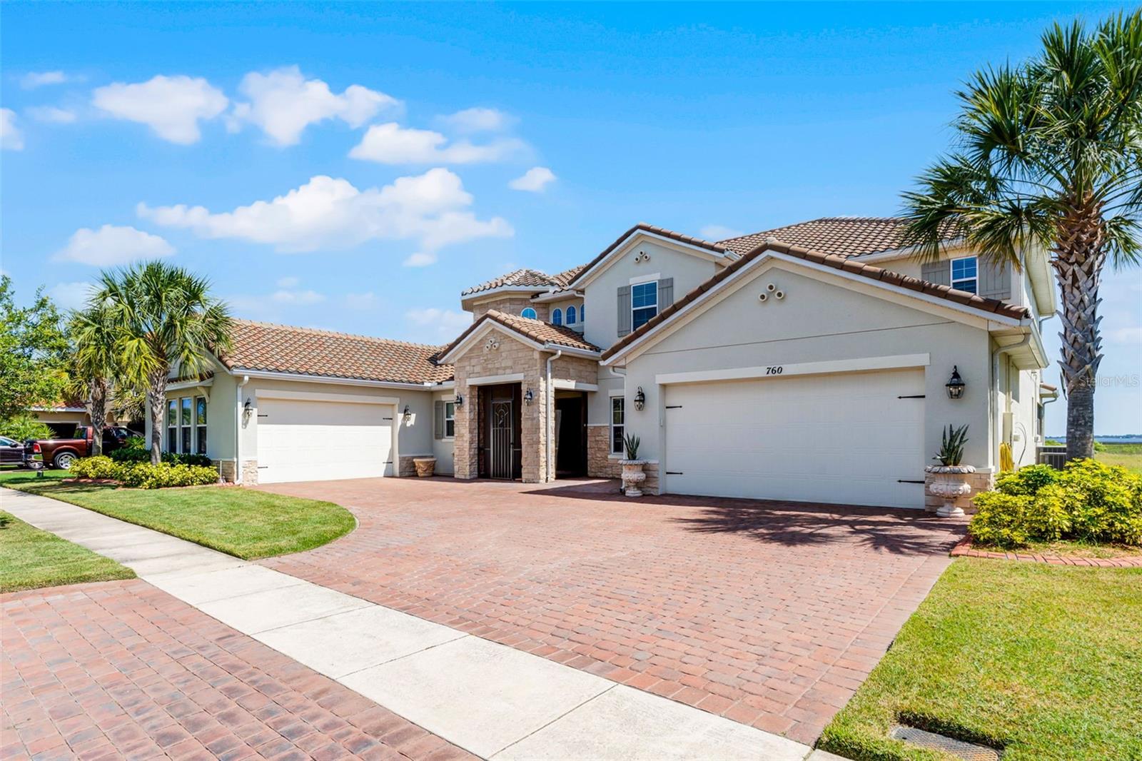 LAKEFRONT LUXURY LIVING in Bellalago! Welcome to this expansive Mediterranean-inspired estate set directly on Lake Tohopekaliga. Built in 2019, this stunning 5,412 sq ft home combines timeless architecture with modern function—offering two 2-car garages, including one oversized with a built-in workshop—perfect for car enthusiasts or hobbyists.Step inside through the gated and screened entry to find soaring 20-foot ceilings and wide-plank flooring that carries throughout the main level. The open-concept design blends formal and casual living beautifully, from the elegant dining area with a dedicated coffee or wine bar to the oversized great room—ideal for hosting large gatherings.The gourmet kitchen is a chef’s dream, featuring 42” cabinets, a glass tile backsplash, granite counters, stainless steel appliances, a walk-in pantry, a butler’s pantry, and a massive island with seating for the whole family. A cozy breakfast nook completes the space, opening seamlessly to a sprawling, screened-in lanai with breathtaking lake views. Enjoy relaxing evenings in the spa under the stars, or add your dream summer kitchen—gas and water lines are already pre-plumbed.With direct access to Lake Toho, boating enthusiasts will love the permitted egress—just add your own dock and hit the water anytime, day or night.The main-floor primary suite offers privacy, its own climate control, a separate entrance to the patio, a spacious custom closet with built-in seating, and a luxurious en-suite bathroom with dual vanities, a soaking tub, water closet, and oversized walk-in shower. A versatile flex room on the first floor is perfect for a home office, studio, or guest space.Also on the main level: a convenient cabana bath, powder room, and full laundry room. Upstairs, you'll find a second full laundry room, a large loft that works perfectly as a media room or lounge, and access to a covered, screened balcony with more panoramic lake views. The junior primary suite features its own full bath, while the remaining bedrooms are generously sized—each with large walk-in closets and shared or en-suite bathrooms. Bedroom 5 also has direct balcony access.Storage won’t be an issue, with multiple storage closets throughout the home—two downstairs and four upstairs.Enjoy the best of resort-style living in Bellalago, a gated waterfront community with a private boat ramp and lift, multiple pools, fitness centers, basketball and tennis courts, a lakeside boardwalk, on-site dining, playgrounds, a dog park, and so much more. Call today to schedule your private tour and experience lakefront elegance firsthand!