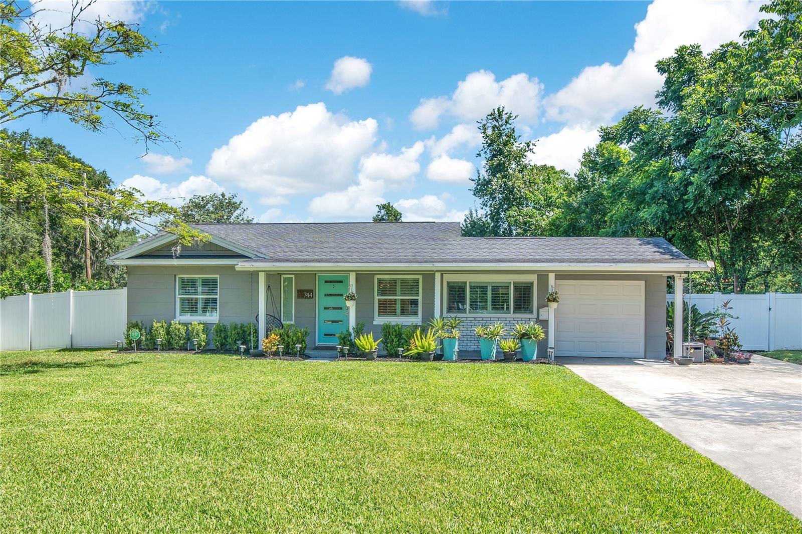 This is the one you’ve been waiting for. In the heart of Lake Como, tucked between the Hourglass and Milk Districts, this 2-bedroom, 1.5-bathroom home sits just one block from Lake Como K-8 and Lake Como Park. The location hits — walkable, central, and zoned for top schools.
The curb appeal? It speaks for itself. Gray exterior, crisp white trim, bold turquoise door, and a covered front porch that offers a proper welcome. Framed by clean, updated landscaping — this home makes you want to slow down… and step inside. Inside, bamboo floors and 6” baseboards run throughout, keeping the flow clean and consistent. The living room gets great natural light through a large front window, with a shiplap accent wall and updated lighting that give it just the right amount of personality. The dining space is a wide, light-filled corridor framed by a warm wood ceiling beam and recessed lighting, with sightlines that pull you straight into the family room. The kitchen is bright, fresh, and connected — pairing a pass-through window with elongated hex tile, white shaker cabinetry, and stainless steel appliances. Every detail is intentional, making it as functional as it is stylish. In the family room, a whitewashed brick wood-burning fireplace takes center stage, bringing warmth and character to the space. Tucked just off the family room and hidden behind a barn-style door, the half bath makes a statement with oversized black hex tile and crisp white finishes — a high-contrast surprise in half the space. The main bathroom blends timeless and modern with floor-to-ceiling subway tile, a frameless glass shower, penny-tile floor, and a bright, spa-like feel that nails the details. Both bedrooms are bright and versatile, with modern ceiling fans and custom closets that make style and storage look effortless. Out back, the living space expands. A covered porch offers shade in the heat, shelter in the rain, and room to relax, dine, or entertain. Beyond it, the fully fenced backyard stretches wide — an open expanse of green with space for play, pets, gardening, or even a future pool. Private, practical, and made for every season. All of it in a location that’s hard to beat — between the Hourglass and Milk Districts, with quick access to 408 and I-4. You’re minutes from coffee shops, craft breweries, markets, and neighborhood favorites. Zoned for sought-after Lake Como K-8 and Boone High School (Go Braves!), this address delivers both lifestyle and convenience.