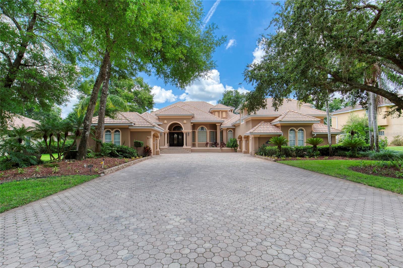 Quality meets opportunity seldom seen with an ASSUMABLE VA LOAN of $860,000 at a 2.375 percent interest rate!! Crafted by a local builder as their personal residence, this exquisite property rests within the gated community Estates of Ormond Lakes. From its lush, manicured landscaping to its distinguished architectural details, every aspect exudes sophistication and warmth. Custom ornate steel doors open to a grand living area with soaring 14+ foot ceilings, rich wood flooring, stepped crown molding, and triple sliders framing views of the sparkling pool with its remarkable multi-level waterfall feature. At the heart of this home lies an extraordinary chef's kitchen, showcasing 42' ivory & cappuccino cabinetry, quartz and granite counters, tile backsplash, a Thermador gas range, GE Monogram commercial-grade refrigerator with custom panels, beverage fridge, new microwave, dishwasher, & a spacious walk-in pantry. The kitchen flows seamlessly into the elegant dining area and family room
featuring custom woodwork and a wet bar, all overlooking the covered lanai, pool, and spa - creating an effortless setting for refined entertaining. The primary suite is a sanctuary of calm, privately tucked away with a sitting area, sliders opening to the pool, two walk-in closets with custom shelving,and a luxurious bath designed for relaxation and rejuvenation. At the front of the home, a versatile office, den, or bedroom with a bay window also serves as the central hub for the hard-wired security system accommodating up to 32 cameras. Two en suite guest rooms are positioned off the family room - one offering pool access, the other opening to a private garden courtyard for moments of quiet retreat. Beyond the kitchen, a well-appointed laundry and mudroom leads to a separate versatile suite with a walk-in closet, full bath, and kitchenette, ideal for guests, a media room, or private workspace. Throughout, you will find dramatic ceiling details, elegant plantation shutters, wood flooring, enhanced trim, upgraded lighting fixtures, and refined finishes that speak to the quality of this remarkable home. Additional highlights include a whole house generator, central vacuum with new motor and components, three-zone HVAC, landscape lighting, and plumbing ready for an outdoor kitchen. The expansive 851 sq ft FULLY climate-controlled attached garage features two large storage closets and a brand-new gym, while a detached 318 sq ft garage offers abundant built-in storage for hobbies or seasonal needs. Ormond Lakes is renowned for its natural beauty and amenities that promote an elegant outdoor lifestyle with scenic sidewalks, pickleball and tennis, community pool and clubhouse, and tranquil lakes brimming with wildlife. With effortless access to I-95, and moments from pristine beaches, fine dining, and recreation, this home offers a rare opportunity to experience timeless elegance and gracious living. Room sizes are approximate; all information obtained through public records and tax rolls and is intended to be accurate but cannot be guaranteed.