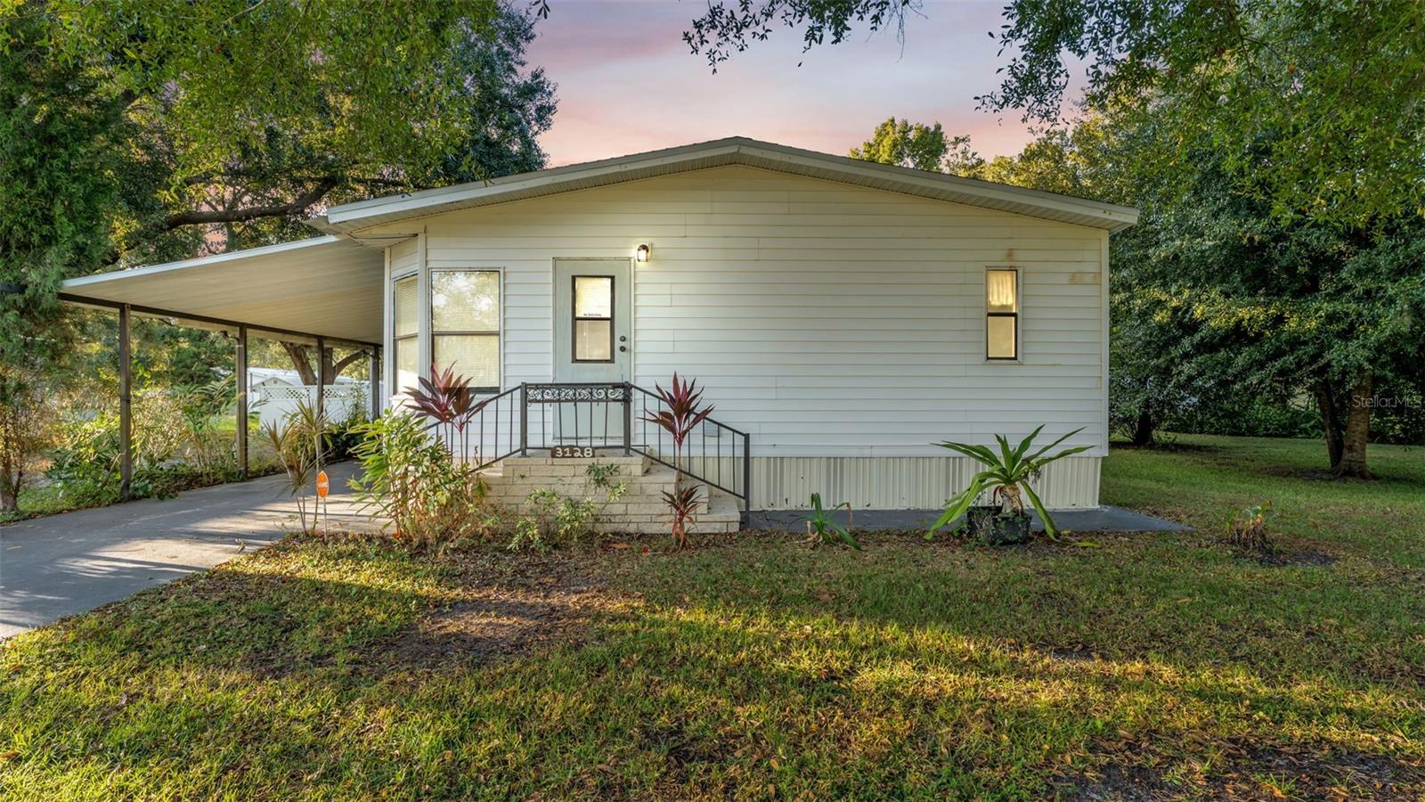 Adorable North Lakeland manufactured home! With some TLC, this property has lots of potential! New Water Heater 2022 and Roof was replaced 5 years ago. This spacious 3-bedroom, 2-bath double-wide, built in 1989, offers 1,512 sq. ft. of living space on a generous 0.26-acre lot with beautiful trees providing plenty of shade. Enjoy peace of mind—this property is not in a flood zone and has no HOA! Inside, you’ll find a large, bright sitting room filled with natural light from multiple windows, and a kitchen with ample cabinetry and included appliances—refrigerator, dishwasher, and oven. A washer and dryer are also included and conveniently located in their own laundry closet. The primary suite features an en-suite bathroom with dual sinks, a large soaking tub, and a separate walk-in shower with a built-in shower seat. Ceiling fans throughout add comfort, and double doors open to the backyard, offering great potential for outdoor enjoyment. A carport provides covered parking. Conveniently located just minutes from I-4 and US-98, shopping, dining, Walmart, Lowe’s, the mall, and Bonnet Springs Park—plus less than 40 miles to Disney and other major Central Florida attractions. This home has so much to enjoy! Seller is also offering a $15,000 credit towards carpet replacement, repairs, buyer closing cost and or buy down.