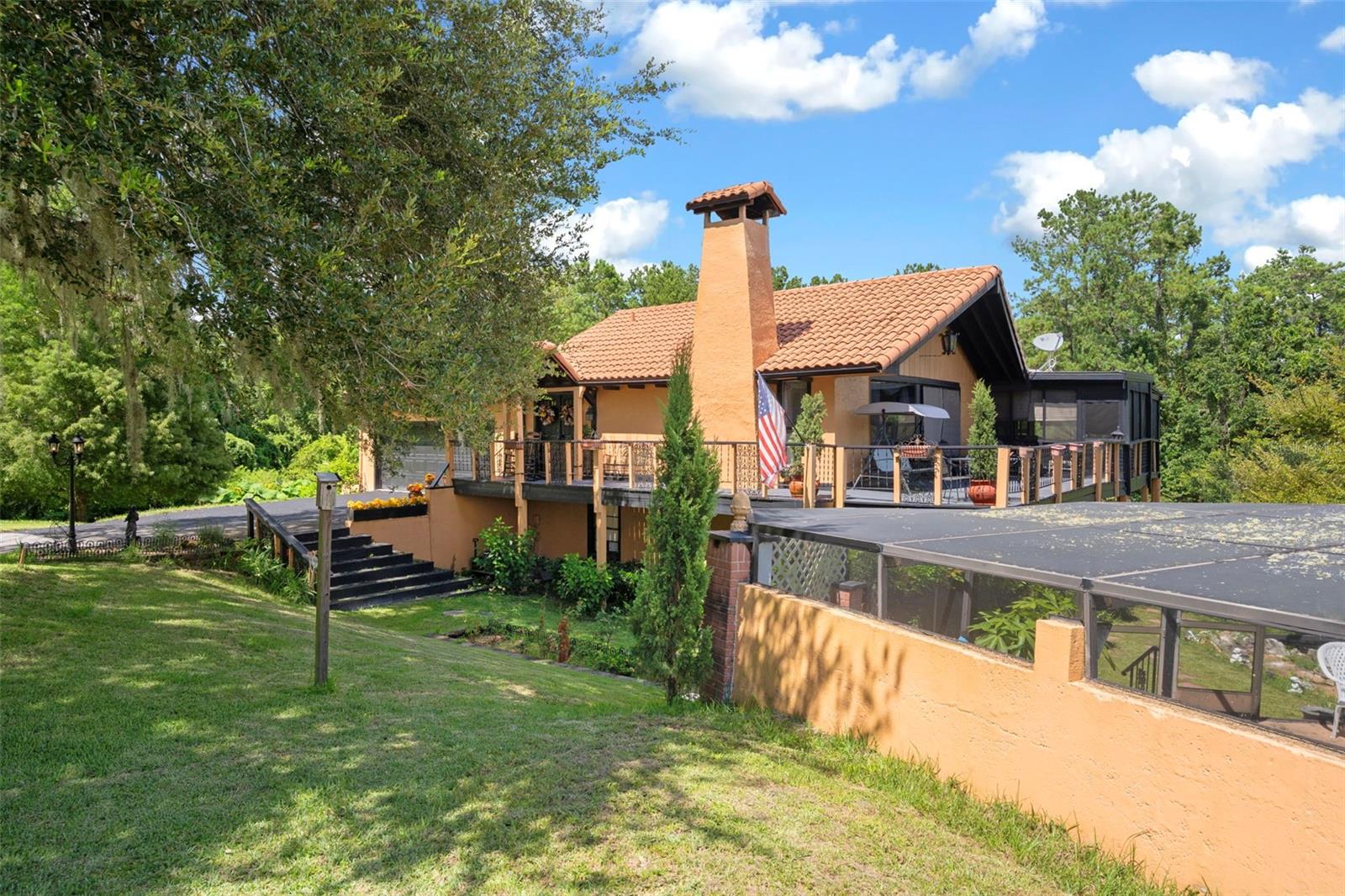 MUST SEE ONE OF A KIND POOL HOME!! Tucked away on 3.4 acres of private, wooded land with a long driveway, this truly unique two-story home is built into a hill and offers a lifestyle that perfectly blends seclusion, comfort, and functionality. Step inside through the main level foyer and you're welcomed into a spacious living room with vaulted ceilings, a cozy gas-burning fireplace, and oversized sliding glass doors leading to the wraparound porch where you can take in sweeping views of the property. A portion of the porch is screened and covered with ceiling fans, creating the ideal spot to enjoy summer evenings surrounded by nature. Off the living room, the dining area provides plenty of room for hosting gatherings, while the kitchen features a breakfast bar, stainless steel appliances, and a large pantry. The main floor also includes a versatile room currently used as a formal dining space but easily convertible to a bedroom, as well as a conveniently located laundry room. Heading downstairs, the lower-level houses four bedrooms and three full bathrooms, including the spacious primary suite with sliding glass doors that open to the back patio and provide easy access to the OVERSIZED screened-in pool, above ground spa, and lounging area. With TWO 2-car garages, a large pond area in front that currently does not hold water, a built-in generator that powers most of the home, and solar panels keeping the average electric bill around $150 a month, this property balances utility with charm. Whether relaxing on the porch, entertaining by the pool, or enjoying the quiet of the surrounding woods, this one-of-a-kind home offers both privacy and convenience with features rarely found together.
