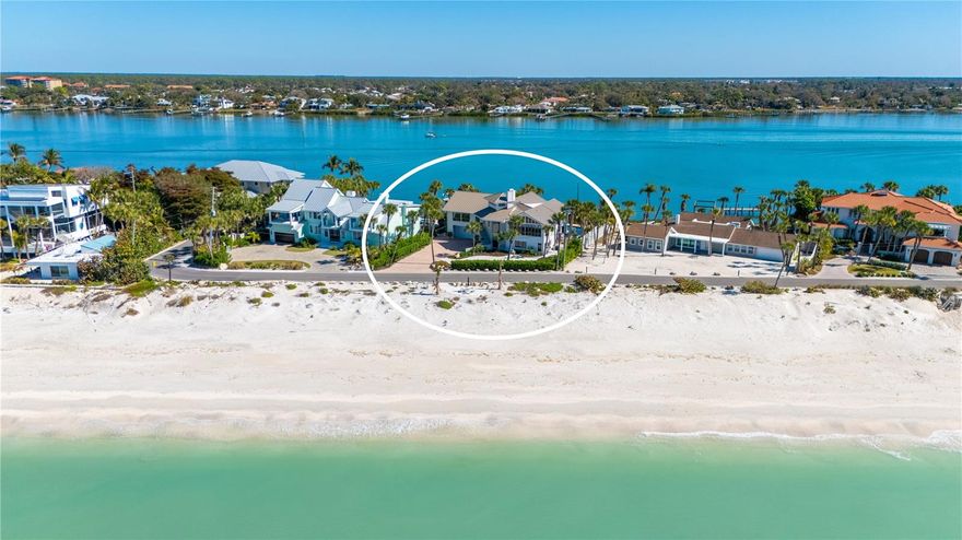 Gulf-to-Bay estate on Casey Key offering rare, deeded private beach access a few steps from the front door and deep-water frontage on Blackburn Bay. Set on more than a half-acre, this elevated coastal residence spans more than 5,500 square feet and delivers a true dual-waterfront lifestyle with boating on one side and the Gulf of Mexico on the other.
The bayfront setting is designed for outdoor living and entertaining, featuring a multi-level tropical environment with expansive pavered decks, covered lounge areas, a gazebo dining space with fully equipped summer kitchen and built-in grilling station, and an open pool terrace with heated swimming pool and spa (resurfaced with a PebbleTec finish). A second-level screened bayfront patio provides a tranquil vantage point overlooking the water. The extended dock, updated in 2018, includes a lift and offers deep-water access with no fixed bridges—ideal for sailboat or powerboat use and direct passage to the bay and Gulf.
Inside, cathedral ceilings and walls of oversized impact windows and sliders frame sweeping views of the bay while filling the home with natural light. The layout is well suited for guests and multi-generational living. The first floor includes a family room, game room, two guest bedroom suites, office with built-ins (that can also be used as a fourth bedroom), and a convenient kitchenette. The second floor is dedicated to the main living spaces, featuring a bay-view living room, dining room, granite kitchen with island and informal dining area, stainless steel appliances, wet bar with wine cooler, and the primary bedroom suite with en-suite bath. A three-stop elevator and stair access connect all levels.
Significant updates include a metal roof replacement (2022), multiple A/C changeouts (2017–2024), replacement of non-impact windows with Anderson impact windows, updated dock pilings and lift pilings, new ductwork, electrical upgrades, and re-piping—providing long-term confidence for coastal ownership.
Located on the quiet southern end of Casey Key, this estate offers a private island setting while remaining close to everyday conveniences. Enjoy easy access to Nokomis Beach, Venice Island dining and shopping, marinas, and the Legacy Trail. Downtown Sarasota’s cultural venues, golf courses, and waterfront attractions are within a short drive, making this a distinctive opportunity to enjoy Gulf beaches, boating, and refined coastal living in one of Sarasota County’s most exclusive barrier-island communities.