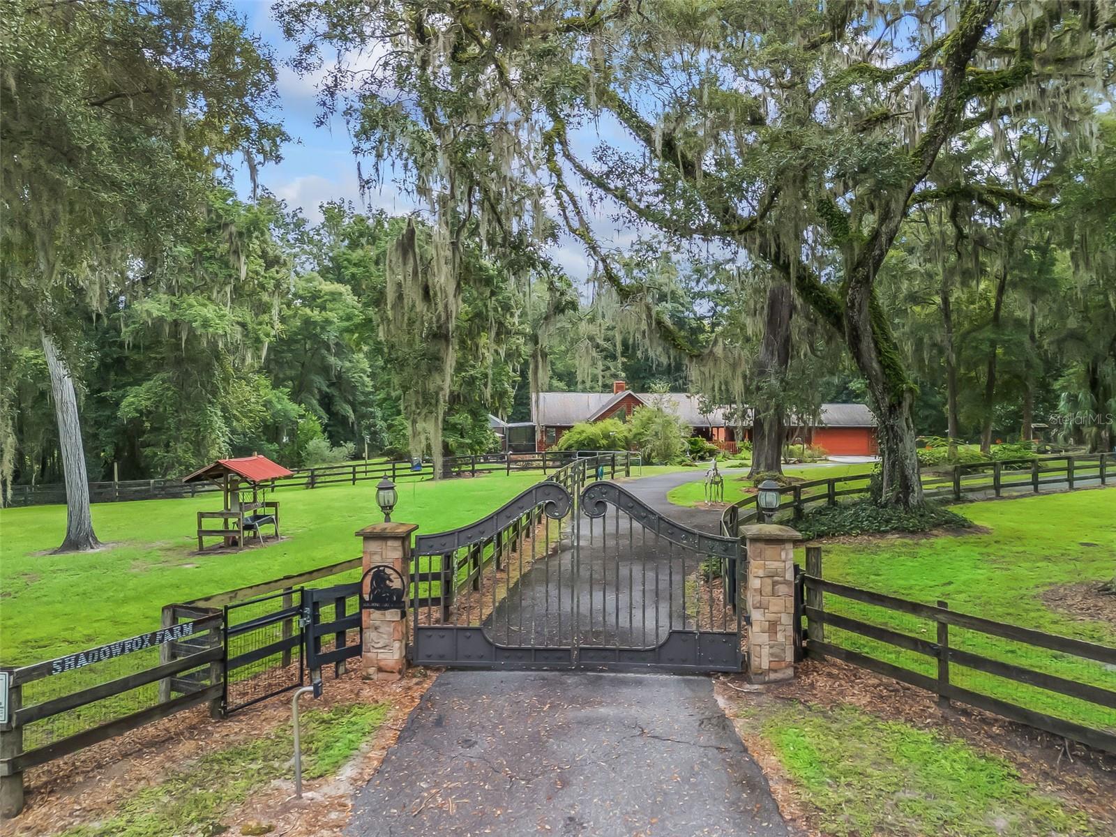 Welcome to this charming and private 2.4 acre farm in the highly sought-after Meadow Wood Farms community! Nestled under beautiful oak trees, this cedar-sided home has been freshly stained and features brand-new decks on the wraparound porch, which overlooks a large screened-in heated pool—perfect for relaxing and entertaining.
Inside, the 3-bedroom, 2-bath home gives a grand lodge feel with its soaring ceilings, double-sided fireplace, and abundant natural light from all the windows. The kitchen is designed for functionality with a spacious island, ample storage, and a cozy eat-in area. A split-bedroom plan and hard-surface flooring throughout make this home both stylish and practical. The primary bedroom has a large walk in closet with a closet organizer system and a large bathroom. Many updates throughout including the AC(2024), Echo RO water softener system, 50 amp breaker in the garage, hardie board siding and metal roof on the barn, plumbing in the living room for a wet bar, septic recently pumped, 4pt inspection and wind mitigation completed, and more. This home and pool area is all handicap accessible.
For added versatility, there’s a separate room off the garage that can serve as an office or be converted into an efficiency apartment. Equestrians will love the well-appointed 4-stall barn featuring an A/C tack and feed room, large stalls, automatic waterers, wash rack, three paddocks with water, and separate gated access for easy trailer parking. There’s even a charming she-shed workshop with a newer roof!
Located minutes from the World Equestrian Center, HITS, shopping, and dining, this incredible property is in a welcoming horse community with a very low HOA. Bonus: the seller is offering an assumable mortgage with an amazing rate!
This farm truly has it all—comfort, character, and convenience in the heart of Ocala horse country!