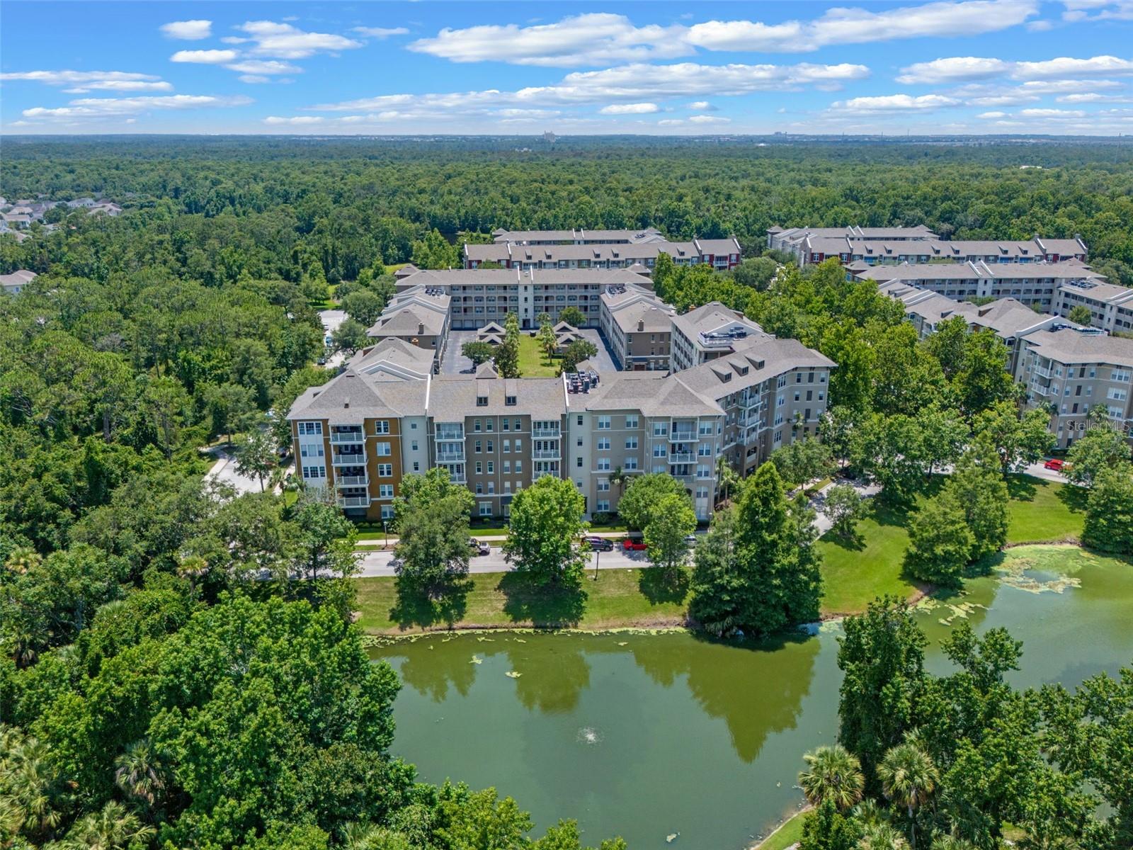 Stunning Penthouse-Level Corner Condo with Expansive Views in Celebration, FL. Welcome to the pinnacle of luxury living in Celebration’s coveted Artisan Park. This exceptional top-floor residence offers over 2,000 square feet of thoughtfully designed living space—all on one level—with sweeping views of lush conservation and tranquil water from its private corner perch. Step inside and experience the light-filled ambiance only a corner unit can provide. Soaring ceilings and expansive windows create a breathtaking sense of space, while gleaming hardwood floors and custom stone accent walls add warmth and character. The open-concept floor plan includes three generous bedrooms, 2.5 beautifully appointed baths, and a spacious flex room perfect for a home office, studio, or library. The oversized, extended balcony is a true showstopper—large enough to function as an outdoor living room or alfresco entertaining space. Whether sipping morning coffee or hosting evening gatherings, this serene treetop setting makes every moment feel like a retreat. The primary suite is a sanctuary in itself, complete with an enviably large walk-in closet that rivals the size of a guest room. A private garage offers secure parking and additional storage, and the solid concrete block construction ensures peace of mind and durability. Additional highlights include elevator access for convenience, updated lighting throughout, and washer and dryer included. Located in the heart of Artisan Park, residents enjoy exclusive access to private clubhouse amenities including a resort-style pool, fitness center, and café. Beyond the building, Celebration offers over 26 miles of nature trails, multiple community parks, playgrounds, pools, and a vibrant town center filled with dining, shopping, and year-round events. Experience a lifestyle of elegance, comfort, and natural beauty—all just minutes from the all the excitement that Central Florida has to offer.