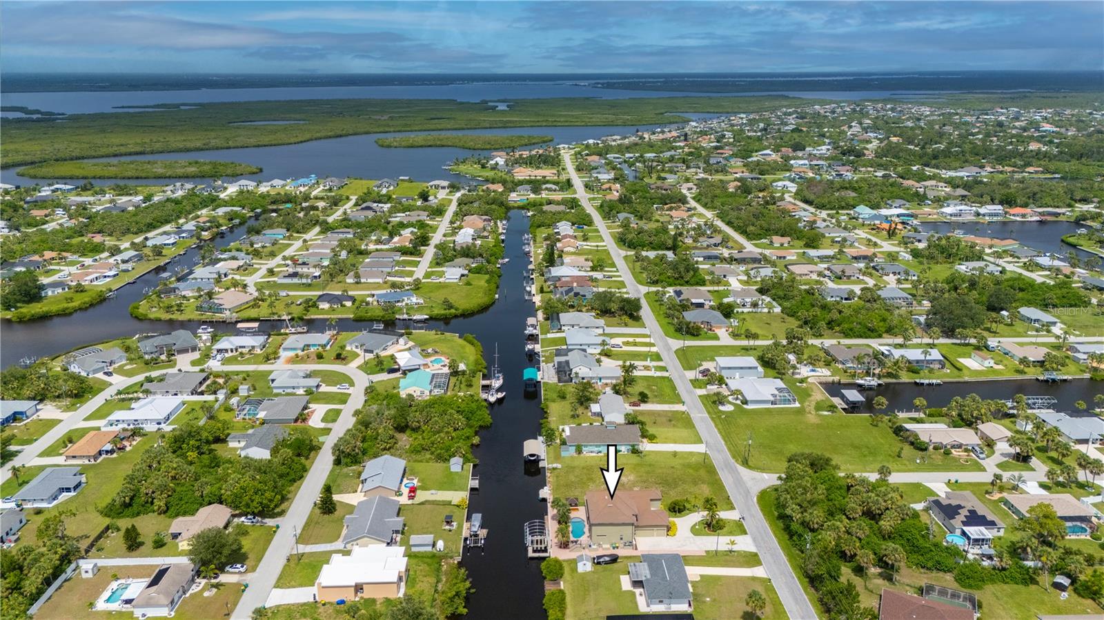 Some homes quietly check the boxes. Others stir something deeper the moment you arrive. From the soft rustle of palm fronds in the breeze to the glint of sun dancing across the canal, this custom 4 bedroom, 4.5 bathroom, 3 car garage waterfront estate in the Port Charlotte Beach area offers more than luxury- it offers a coastal sanctuary. Sailboat-accessible with no fixed bridges, 80 feet of waterfront, and a private 60ft dock with a 24,000lb lift, this is a property designed for those who feel most at home on the water-yet crave elegant living on land. Every inch of this residence reflects thoughtful design and enduring craftsmanship. The entry opens into soaring, light-filled spaces framed by arched passageways, tray ceilings, and stately columns. An elegant double-sided gas fireplace warms both the formal dining room and private office, while plantation shutters, crown molding, and curated finishes add warmth and sophistication. The heart of the home is its gourmet kitchen, seamlessly blending form and function. Solid wood cabinetry, granite countertops, and stainless steel appliances are complemented by an induction cooktop, built-in oven, microwave, warming drawer, and a wine bar with a wine fridge. Whether you're hosting holiday dinners or quiet evenings for two, the layout invites connection and conversation. The first-floor primary suite feels like a private wing, with a spacious walk-in closet and a spa-like bath that features a jetted soaking tub, Roman-style shower with multiple heads, and dual vanities. Upstairs, three oversized bedrooms and two full baths offer privacy and flexibility for family or guests. One bedroom enjoys an en suite, while the other two share a Jack-and-Jill layout. A secluded loft with a balcony offers a peaceful perch overlooking the pool-a perfect morning retreat or creative hideaway. Step outside and the story deepens. A screened porch with double doors leads to the lanai with a heated saltwater pool framed by paver decking, lush tropical landscaping, and a custom tiki hut with a fully equipped outdoor kitchen. It’s a space built for memory-making-from sunlit pool days to starlit dinners by the water. And beyond the beauty? The peace of mind that comes with knowing this home has been impeccably maintained: a new tile roof (2022), impact-resistant windows, new A/C systems with zoned climate control, new pool heater, pump, and salt system, new carpeting, and fresh interior and exterior paint. A circular paver driveway and side-loading 3-car garage offer convenience and curb appeal in equal measure. With no HOA, no deed restrictions, and no flooding or hurricane damage from recent storms, this home offers rare freedom along with its luxury. And the location places you just minutes from Port Charlotte Beach Park, the Sunseeker Resort, golf courses, restaurants, Punta Gorda airport, I-75, and the charm of historic downtown Punta Gorda. Whether it’s a full-time residence or seasonal escape, this is more than just a place to live—it’s a setting for the life you’ve worked hard to create.