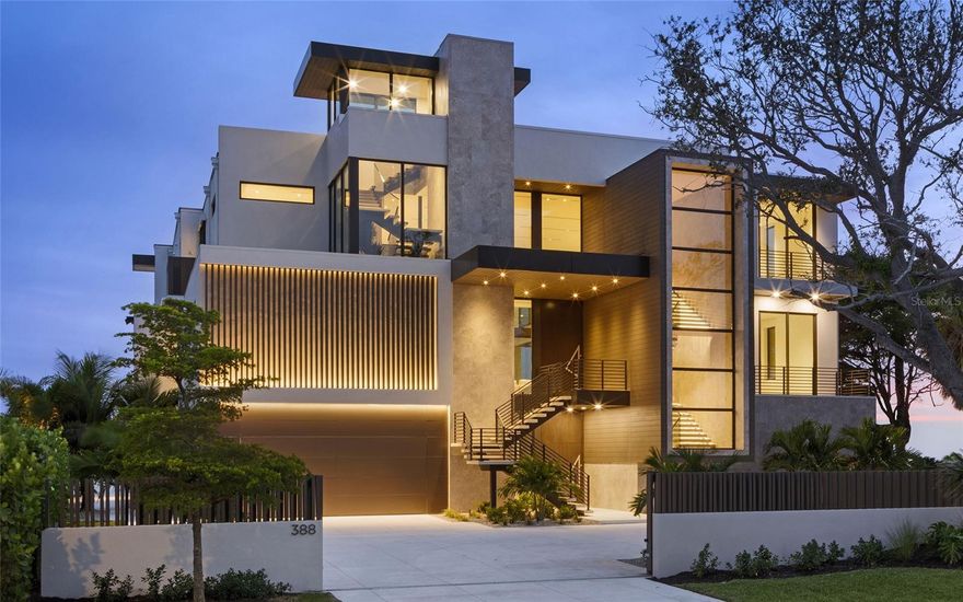 World-renowned as Florida’s cultural coast, Sarasota’s heritage of culture and the arts provides a distinguished backdrop for its newest architectural tour de force – Lunara. Set in Sapphire Shores, one of Sarasota’s most historic and culturally rich neighborhoods, the location is quintessentially Sarasota. This prized location, originally chosen by one of the city's foremost visionaries for his own Ca' d'Zan mansion, commands what are widely regarded as the city's best views, with sweeping panoramas of Sarasota Bay, the downtown skyline, and the landmark Ringling Bridge. Steeped in a tradition of the future, Lunara transforms state-of-the-art materials from around the world through the enduring craft of local artisans. Designed by Mark Sultana of DSDG Architects and built by Michael Voigt of Voigt Brothers Construction, the residence reveals itself with dramatic geometry and floating planes. Every angle captures the shimmer of water, every surface plays with light, and every room welcomes you into a life surrounded by beauty. The heart of the home opens with dramatic presence — the 11-foot pivot entry door leads to a soaring double-height living space, where an 11-foot automated glass wall extends to an equally lofty trellised sun deck. Despite its scale, the residence feels warm and personal, thanks to a no-hallway design directive that connects each area with purposeful flow. The impressive entertainment bar, which features floating liquor display shelves and a climate-controlled wine display, stands distinct yet linked to the ultra-high-end kitchen, which includes a retractable pass-through to a concealed prep kitchen. Outside, the al-fresco kitchen and pool deck share the same floor level as the interior, creating a connected indoor-outdoor living experience that amplifies the home’s spacious elegance. Lunara’s pleasures are abundant, anchored by amenities that blend function with imagination. A two-level swimming pool cascades from infinity edge to lap lane, offering a visual spectacle as much as a place for play or exercise. The glass elevator, tallest of its kind in a Sarasota residence, glides between levels with clarity and grace. The 10-car garage is designed to be more than just storage with bay-facing sliding glass doors that invite fresh breezes, natural light and a perfect view to enjoy while caring for your prized collection. The rooftop deck, a stage for Sarasota’s sunsets, invites leisure and entertainment in equal measure, complete with a putting green, fire pit and a flex space adaptable to yoga at dawn or cocktails at dusk. Even the practical touches are elevated – a dedicated “Christmas tree closet”, concealed floor-to-ceiling doors, and a movable wall of privacy glass that transforms the primary bath into either open vista or private retreat. Beyond prestige, the best of Sarasota is always close at hand. Within one mile you’ll find SRQ International Airport and The Ringling Museum. Downtown Sarasota, The Bay park, and Marina Jack are just five miles away, with Sarasota Memorial Hospital, St. Armands Circle and Lido Beach within six miles. IMG Sports Academy and St. Stephens School are within eight miles from your door. It is rare to find a residence that is at once a work of art and a place of retreat, where scale feels human and luxury feels livable. In Lunara, architecture becomes lifestyle, and lifestyle becomes sanctuary. This is a home that does not merely impress, it endures.