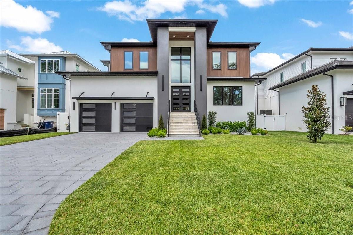 This newly completed 5,000+ sq ft Sunset Park home by Gloger Construction offers luxury and peace of mind with premium builder upgrades including a whole-home 22kW GENERAC GENERATOR, GARAGE CAR LIFT, and FLOOD INSURANCE PREMIUM COVERED FOR 1 YEAR. Designed above FEMA standards with double block construction and hurricane-impact windows, it features 5 bedrooms, 5 full baths, 2 half baths, a dedicated office, and a spacious upstairs bonus room. The open-concept living area includes a TEMPERATURE CONTROLLED WALK IN WINE ROOM, and a gas fireplace, flowing seamlessly to a balcony and outdoor kitchen overlooking the pool and spa. The chef’s kitchen boasts Thermador appliances, quartz counters, and a hidden butler’s pantry. A first-floor primary suite offers a spa-like bath, walk-in closet, and balcony access—all just minutes from top-rated schools and local dining.