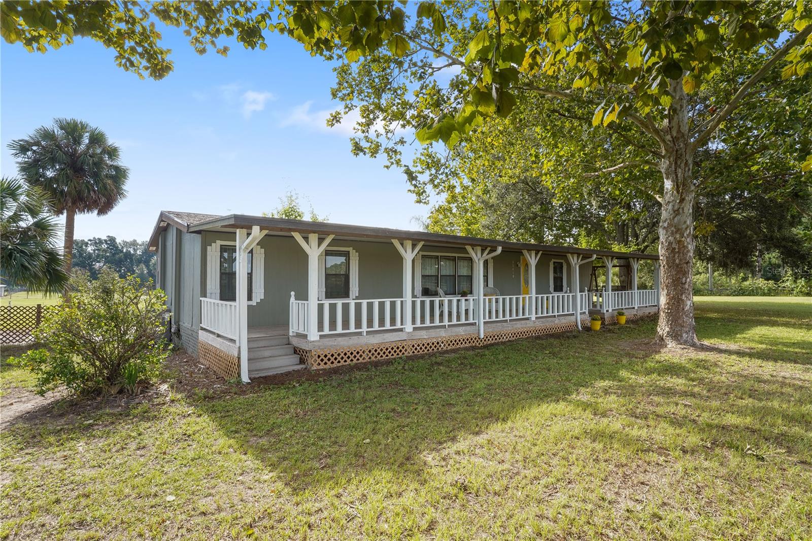 Welcome to 35410 Johns Lane, a peaceful Eustis retreat where country charm meets functionality on over 5 acres of open land. This 3-bedroom, 2-bathroom modular home is perfect for those seeking space, privacy, and room for their four-legged friends. The home offers covered front and rear decks, providing the ideal setting for enjoying Florida's breathtaking west-facing sunsets. Step inside to find a spacious kitchen featuring a center island, 4-burner cooktop, and built-in oven, making cooking and entertaining a breeze.
Equestrian enthusiasts will love the clay-based arena, 4-stall barn, Tac room, and tractor shed – all designed for ease and functionality. The metal shed adds additional storage options, while the barns boast brand-new roofs (2023) for added value and peace of mind. Explore the land, or relax under the stars – this property is a lifestyle, not just a home.
Recent updates like the new water heater add comfort and efficiency, while the surrounding landscape – backing to a tranquil tree farm – offers ultimate privacy and a scenic backdrop. Families will love the convenience of having a top-rated school with a short distance, making mornings simple and stress-free.
Whether you're dreaming of a mini farm, a quiet retreat, or your forever home, 35410 Johns Lane delivers. Don’t miss this one-of-a-kind opportunity to own your own slice of Florida paradise with room to grow, play, and live fully. **Home does have pool, however being sold as is**