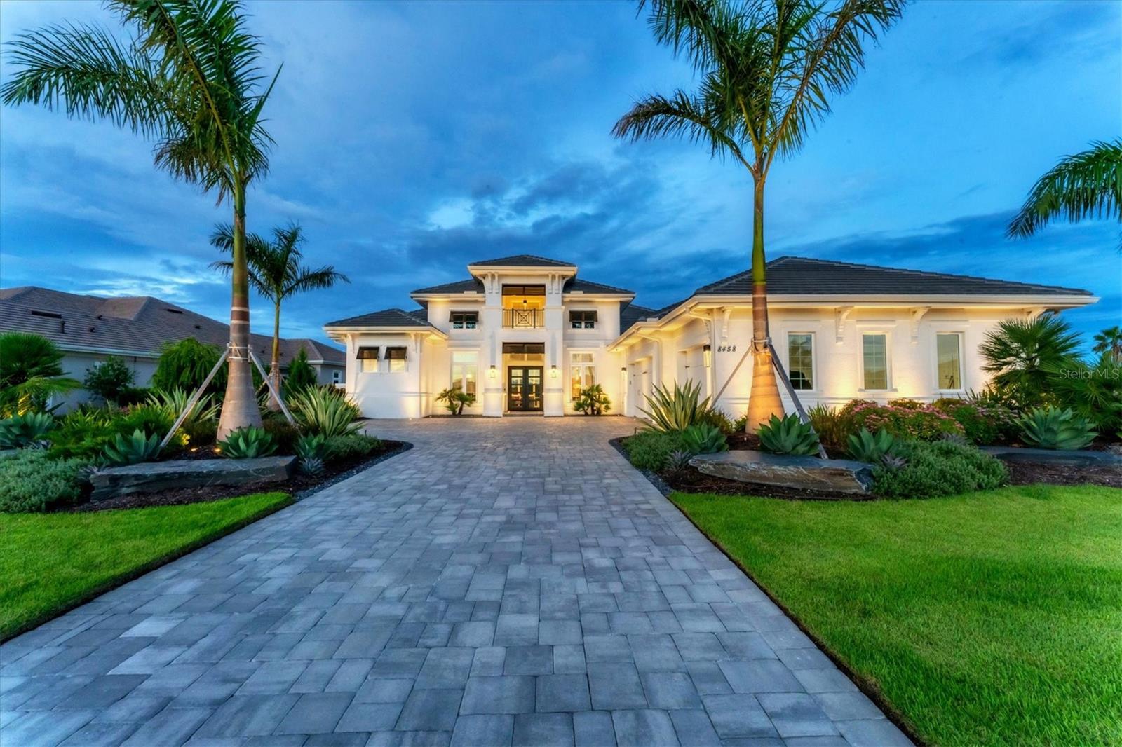 This custom home offers complete privacy, with a non-buildable homesite next door and breathtaking, unobstructed water views extending down the lake, ensuring no other homes are in sight. Elevated higher than any other estate on the street, this nearly new residence boasts over 3,800 square feet of luxury living, including three bedrooms, each with an en-suite bath, a study and a bonus room. Every detail reflects thoughtful upgrades and high-quality construction. The meticulously redone landscaping, outdoor lighting, and long paver driveway with parking pad and side-entry garages lead you to the inviting foyer through double glass doors, where stunning lake views immediately greet you. Inside, whitewashed wood floors, 10-foot pocket sliders to the lanai, designer lighting, custom window treatments, electric shades and soaring 16-foot ceilings showcase the home’s architectural elegance. The expansive great room, equipped with a sound system, flows into the gourmet kitchen, featuring high-end appliances including a Wolf built-in oven, steam oven, cooktop, Sub-Zero refrigerator, Bosch dishwasher and a large island with quartz countertops. Additional kitchen highlights include a walk-in pantry, custom backsplash, designer wood hood and breakfast nook. The outdoor living space is a paradise, offering a covered entertaining area with tray ceilings, a cozy fireplace, and a separate patio with a built-in fire pit. With over 80 feet of panoramic lake views, the heated saltwater pool and spa are enhanced by color-changing lights and fire accents, creating a magical nighttime ambiance. The outdoor kitchen, complete with a refrigerator, grill, hood and bar top, is ideal for entertaining, while Kevlar hurricane-rated screens provide protection at the touch of a button. The primary suite is equally impressive, featuring tray ceilings, a wine bar, and French doors with extended sidelight windows opening to the lanai and lake views. Dual custom walk-in closets lead to a luxurious primary bath with a freestanding soaking tub, spacious walk-in shower, dual vanities and a private water closet. The rear bonus room, with oversized windows, offers flexible use as a media room, second office or fourth bedroom. Guests will enjoy their private accommodations with two additional guest bedrooms, each with custom walk-in closets. Additional features include a stately study with French doors, a dining room with a stunning chandelier, and a well-equipped laundry room with ample counter space and cabinetry. Notable amenities include a whole-home water filtration system, a 22-kilowatt Kohler generator, an upgraded security system, electric blinds in office, dining, primary suite and bonus room, solid core doors, custom closets throughout, and an electric car charger in the extended three-car garage with cabinetry. In the prestigious, gated community of Lake Club, residents enjoy access to the Grande Clubhouse, a restaurant, pool, tennis courts, pickleball, a playground, basketball court, fitness center, dog park, and interlinking lakes ideal for kayaking or fishing. This is a home where luxury meets timeless design.