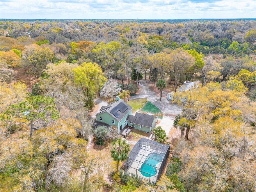 There’s a certain kind of quiet you can’t fake, the kind where mornings begin with coffee on the porch instead of notifications, and the only interruptions are a breeze through the trees and the occasional movement of wildlife across the land. Set in the Glenwood area of northwest DeLand, this 13.3-acre property offers a private, multi-parcel setting where space, functionality, and natural surroundings come together in a way that is increasingly hard to find. The main residence at 2090 Stone Road sits on approximately 2.83 acres and features 3 bedrooms, 2.5 bathrooms, and nearly 2,000 square feet of living space, along with a flexible bonus room that may be used as an additional bedroom, office, or guest space. The home is designed for comfortable, everyday living and includes an attached 2-car garage with mini-split air conditioning, opening to a screened pool and spa overlooking your acreage and creating a private outdoor setting for both quiet mornings and evening gatherings. The adjoining parcel at 2095 Stone Road adds approximately 10.47 acres with established trails, a seasonal stream, and mature citrus trees including orange and grapefruit, extending the property into a natural, usable landscape. Zoned Agricultural (A-3) and fenced with a gated entry, the property supports a variety of potential uses and includes a 49x25 metal garage/workshop, 30-amp RV hookup, chicken coops, and garden area. Additional improvements include paid-off solar panels, a whole-home generator with propane tank, and water filtration and softener systems. While offering a sense of privacy, the property remains conveniently located near downtown DeLand, shopping, parks, trails, and natural springs. It is not remote, but positioned to provide space and distance from surrounding development. Shown by appointment only. Property may be under video/audio surveillance. All information is deemed reliable but not guaranteed and should be independently verified by buyers and their agents, including but not limited to measurements, zoning, land use, parcel details, and any other material facts.