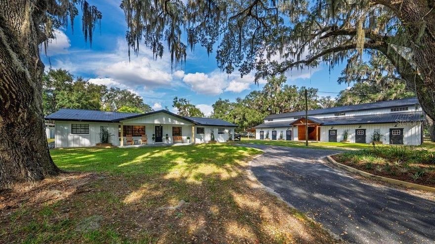 Set beneath a breathtaking canopy of centuries-old granddaddy oaks in Ocala’s coveted Field of Dreams, this extraordinary 7-acre estate embodies the pinnacle of refined equestrian living. Surrounded by immaculate estate farms, the property offers unmatched privacy, natural beauty, and effortless access to the World Equestrian Center, HITS, and everyday conveniences—an exceptional blend rarely found.

A picturesque, oak-lined drive leads to the fully renovated main residence, thoughtfully positioned deep within the property for peaceful seclusion. The impeccably designed 2,000± sq. ft. home features a welcoming front porch, three bedrooms, and three full designer baths, finished with curated materials and timeless elegance throughout. The chef’s kitchen is a true showpiece, boasting premium appliances, a dramatic waterfall island with seating for six, and panoramic views of the majestic oaks beyond. The private primary suite serves as a serene retreat, complete with a generous walk-in closet and spa-inspired bath featuring an oversized walk-in rain shower. A game room and oversized laundry room add both functionality and comfort to the home’s thoughtful layout.

The equestrian amenities are nothing short of spectacular. A meticulously crafted Amish-built, monitor-style barn showcases a striking 24-foot center aisle adorned with chandeliers and clerestory windows, creating a light-filled, dramatic atmosphere. The barn includes twelve spacious 12’ x 12’ matted showcase stalls, dedicated tack and feed rooms, and conveniently located heated-water wash stalls. Just beyond, a 100’ x 200’ natural-footing arena sits beneath a magnificent centerpiece oak and overlooks a serene pond with a fountain, providing a truly postcard-worthy setting.

Designed for both entertaining and relaxation, the pond is complemented by a charming gazebo featuring a full outdoor kitchen with gas pizza oven, BBQ, prep space, sink, and a dock where you can feed vibrant koi—an idyllic place to unwind after a ride or host unforgettable gatherings. Additional equestrian features include two birthing stalls, a workshop/garage, and seven paddocks, six equipped with automatic waterers for effortless care and equine comfort.

A second matching monitor-style barn offers approved plans for conversion into a two-bedroom guest house with office, creating exceptional flexibility for guests, family, or staff. This structure enjoys its own private gated entrance and is paired with a sparkling pool overlooking a serene oak-framed pastoral vista.

Every detail of this remarkable property speaks to intentional design, superior craftsmanship, and timeless elegance—from the board-and-batten farm architecture to the thoughtfully framed oak-studded views and seamless flow of the equestrian facilities. Located in the heart of Ocala’s horse country yet minutes from everything, 8583 NW 130th Street presents a rare opportunity to own a turnkey, luxury equestrian estate in one of the area’s most desirable neighborhoods.