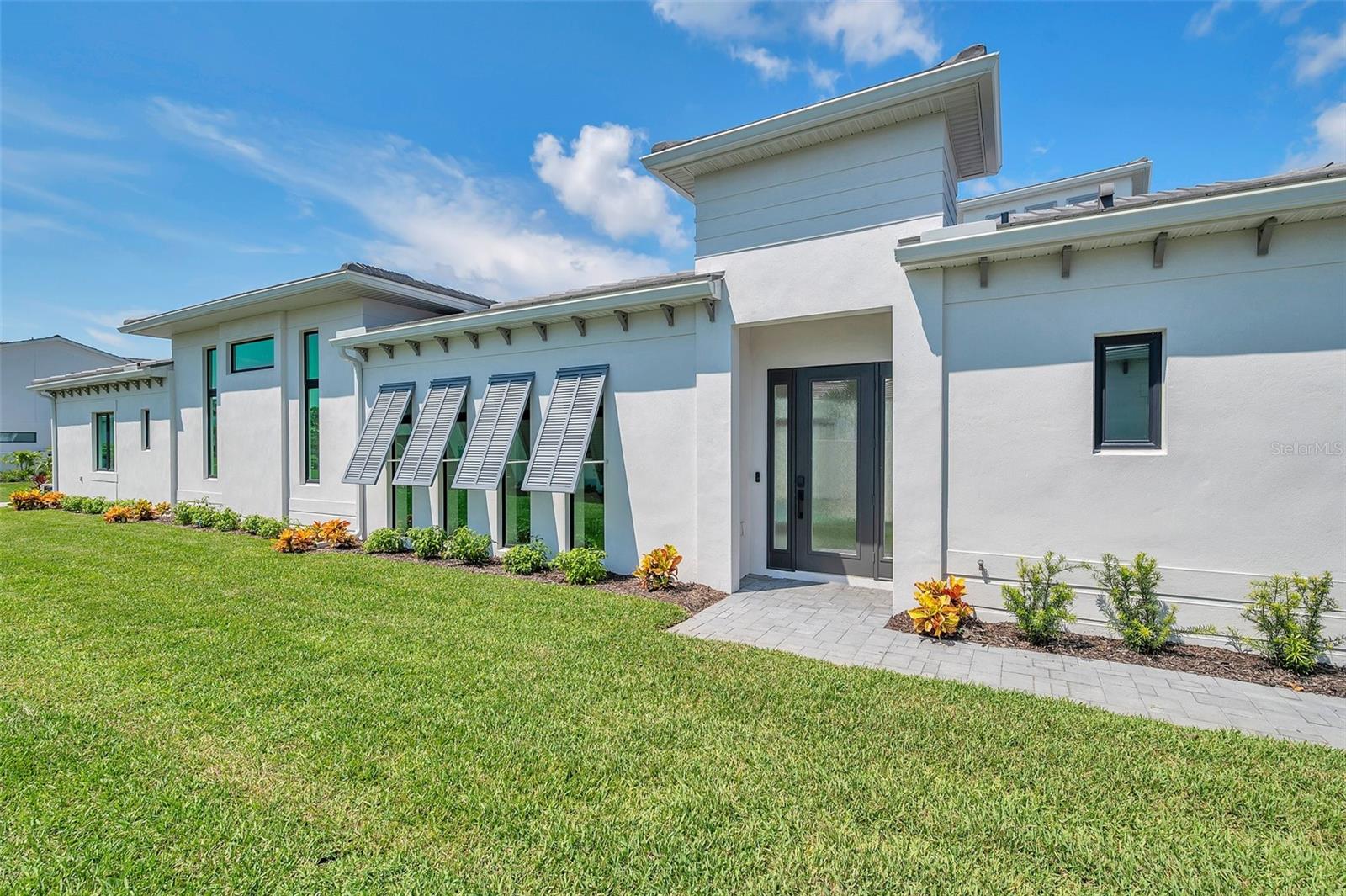 Welcome to this brand-new, never-lived-in home in the gated Aqua community. Built in a non-flood zone with solid block construction, a durable tile roof, and PGT impact windows and sliders, it meets current hurricane codes for true peace of mind. Aqua offers a private 4-acre tropical lagoon for swimming, paddleboarding, and kayaking, and the home is less than 5 minutes to IMG Academy. The property sits directly across from the lagoon for easy access.
Set on an oversized extended lot, the home enjoys extra space, privacy, and more natural light inside thanks to wider side setbacks. This highly customized Sea Grape plan is approximately 250 sq ft larger than the standard model, creating more room where it matters.
The single-level layout includes three bedrooms, three full bathrooms, and a two-car garage. The great room impresses with soaring 14 ft ceilings, while the rest of the home features 10 to 11 ft ceilings and tray accents. A dedicated laundry room adds everyday convenience.
At the heart of the home is an oversized kitchen island surrounded by extended cabinetry, high-end appliances, a gas range, and a built-in wall oven with a convection microwave. Impact-rated sliders from the kitchen and the primary suite stack out of sight to connect the interior with a private courtyard designed for effortless indoor-outdoor living.
The courtyard is a true retreat with a heated spool featuring six jets, smartphone controls, a tranquil waterfall, privacy fencing, and an outdoor kitchen with a gas grill for year-round entertaining.
The primary suite showcases a distinctive blend of hardwood and tile flooring, a large walk-in closet, a free-standing soaking tub, and a shower with a dual-swing glass door.
Additional upgrades include a feature fireplace, an extended garage with a 60-amp EV charging outlet, whole-home spray foam insulation, a micro-leak detection system, and added insulation around the AHU closet. Low HOA dues include fiber internet, TV, and landscaping for a low-maintenance lifestyle.
Do not miss this opportunity to own a one-of-a-kind extended plan on an oversized lot. Schedule your private tour today!