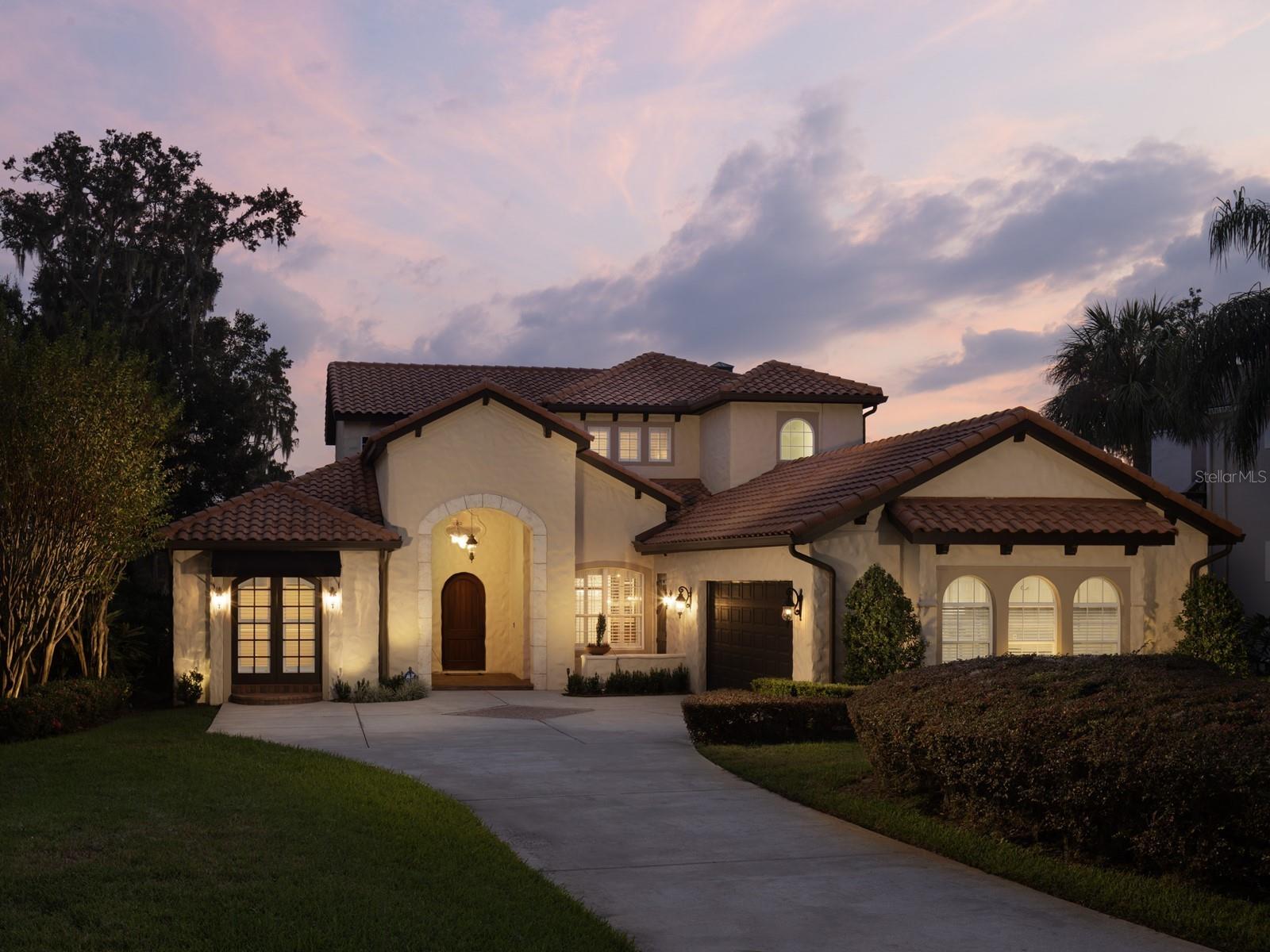 Discover luxury living in this stunning estate located on renowned Lake Butler Blvd, overlooking Wauseon Bay of the Butler Chain of Lakes. Set on close to one acre of beautifully landscaped grounds, this private oasis is designed for both relaxation and entertainment. As you enter through the winding driveway, you'll be greeted by lush landscaping and a detached oversized garage, fully air-conditioned, perfect for car enthusiasts or this space can be converted to a gym, in-law suite or other use. The main residence, custom-built with a timeless exterior, features an additional two-car garage. Step through the beautiful wood entry doors and immediately notice the high ceilings, upgraded wood flooring, and custom millwork that create an inviting atmosphere. The expansive windows in the main living areas provide breathtaking views of the lake. The first-floor primary suite is a true retreat, offering a private sitting area, custom closets, and a spa-like bath. The gourmet kitchen boasts top-of-the-line appliances, custom cabinetry, and stone countertops, seamlessly flowing into the family room and breakfast area, all filled with natural light and stunning lake vistas. Upstairs, you'll find ample storage along with three additional guest rooms, a cozy loft, and a balcony perfect for watching sunsets. The outdoor space is an entertainer's dream, featuring a travertine lanai and pool deck that overlook a massive backyard, private beach, and lakefront. The spacious dock includes a large screened-in sitting room, boat lift, and a floating jet ski dock. Located just a short stroll from downtown Windermere, this estate offers easy access to shops, Windermere brewing, dining, tennis courts, playgrounds, parks, and so much more. Don’t miss this unique opportunity to own a piece of paradise the the Butler Chain of Lakes!
