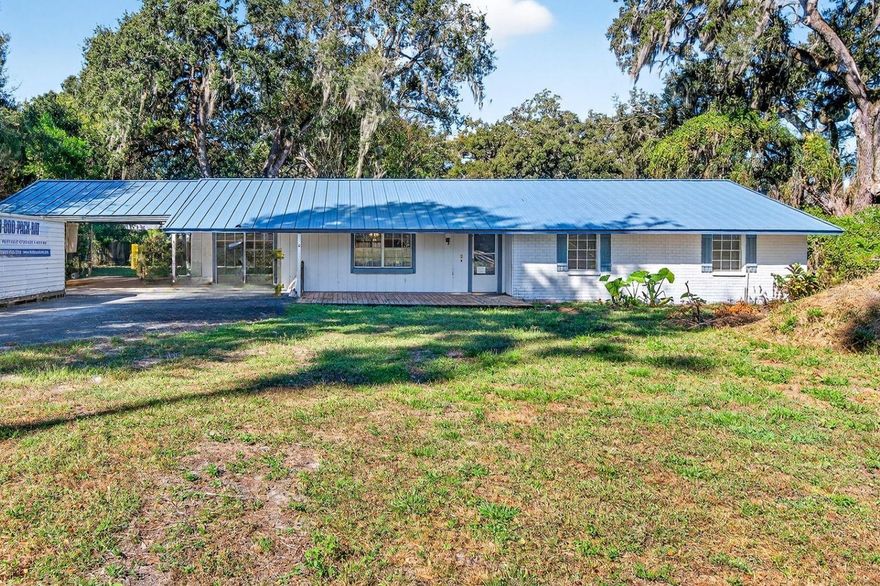 One or more photo(s) has been virtually staged. Welcome to this charming ranch-style home, perfectly situated on just under half an acre with no deed restrictions or HOA fees! Featuring 4 bedrooms, 2.5 baths, and a massive detached garage with water, electric, and multiple workshops, this property is ideal for hobbyists, mechanics, or anyone who loves extra space to create and build.

Step through the front door into a welcoming foyer that opens to a bright and airy living area. The dining room, accented by warm wood floors, sits conveniently off the kitchen—perfect for family gatherings and entertaining guests. The spacious kitchen offers abundant cabinet and counter space, along with a peninsula island and breakfast bar for casual dining and conversation.

The family room impresses with vaulted ceilings, gleaming wood floors, a large bay window, and elegant wood French doors that fill the space with natural light. The French doors open to an enclosed room—ideal as a mudroom connecting the main home to the workshop area—and lead to an expansive Florida room with soaring ceilings and endless potential for entertaining, a game room, or an additional living area.
All bedrooms are generously sized, offering flexible layouts to suit your needs. A separate den provides a cozy retreat for reading, relaxing, or even converting into a 4th bedroom, complete with its own exterior entry.

The indoor utility room includes a washer and dryer, wash sink, and extra storage.
The detached 925 sq ft garage is a standout feature, offering a two-car bay, half bath, a large 24’ x 15’ workshop, and an 18’ x 8’ office—all equipped with water, electric, and air conditioning. There’s also covered storage along the side and back of the garage, plus a long paved driveway and two-car carport for ample parking.

Conveniently located near I-75 and I-4, this solidly built home offers easy access to Tampa, Brandon, and surrounding areas. With plenty of space, functionality, and room to customize, this property is ready to become your forever home.