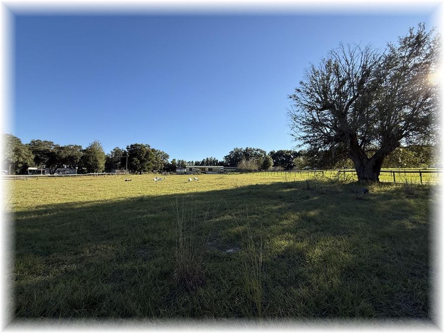 3.4 ACRES – PRIVATE YET REAL CLOSE TO THE VILLAGES – HAS 3/2 DBL MOBILE W METAL ROOF, ATTACHED CARPORT, PLUS 3 DETACHED WORKSHOPS – ALL FENCED WITH 2 SEP PADDOCKS - GATED ENTRYWAY IS NOT PART OF THE PADDOCK AREAS – SO YOUR ANIMALS WON’T GET OUT – DRIVEWAY BRINGS YOU BACK TO 3/2 SPLIT HOME WITH LONG FRONT PORCH OVERLOOKING FRONT PADDOCK – BRINGS YOU INTO FOYER OPENING TO LARGE LIVING RM W CATH CLGS, LAMINATE FLRS AND COZY CORNER FIREPLACE, SEP EATIN KITCHEN HAS LOTS OF WOOD CABS, PANTRY AND ALL APPLIANCES – MASTER BEDRM ALSO HAS LAMINATE FLRS PLUS FULL WALL CLOSETS FOR STORAGE – MASTER BATHRM HAS LONG VANITY PLUS TUB-SHOWER COMBO – ALL GOOD SIZED GUEST BEDRMS HAVE PADDLE FANS PLUS GOOD STORAGE CLOSETS – GUEST BATHRM ALSO HAS TUB-SHOWER COMBO – INSIDE LAUNDRY RM OFF KITCHEN LEADS OUT TO CARPORT FOR PARKING – DET WORKSHOP OFF REAR PORCH FOR STORAGE – PLUS REAR PADDOCK HAS DETACHED WORKSHOP WITH STALLS ALONG WITH ANOTHER DET WORKSHOP – LOTS OF FENCING WITH NEIGHBORS GOATS GRAZING FOR NOW – PERFECT FOR YOURS TOO!