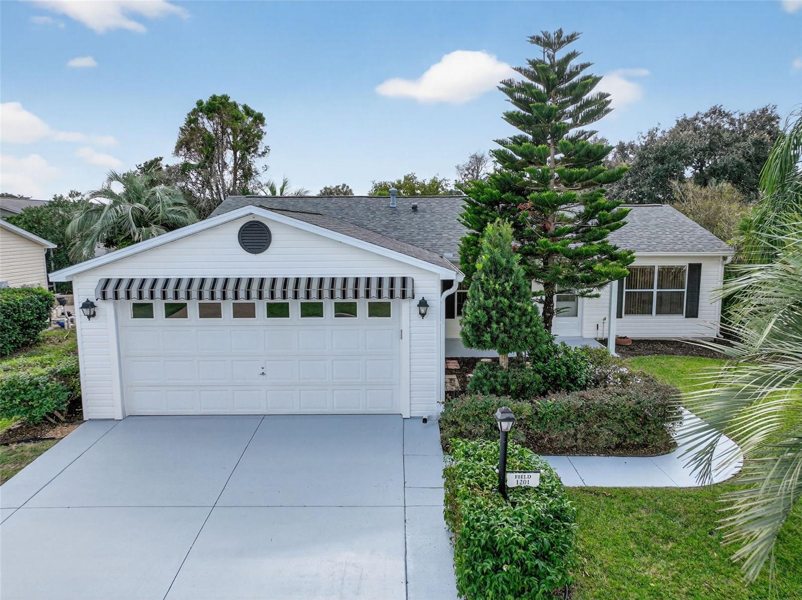One or more photo(s) has been virtually staged. • NO BOND • 2021 ROOF & HVAC • FLORIDA ROOM • ENCLOSED LANAI
Located on a desirable corner lot in the sought-after Village of Santiago, this beautifully maintained 2-bedroom, 2-bathroom Stetson model offers updated systems and a thoughtfully designed layout. A charming covered front porch with a decorative leaded-glass front door welcomes you into an open, split floorplan featuring tile flooring throughout the living, dining, and kitchen areas. The kitchen boasts brand new stainless steel appliances and a convenient breakfast bar, perfect for casual meals and entertaining. Enjoy year-round comfort in the added Florida Room with new carpet, or relax in the enclosed lanai that opens to a private outdoor patio with a pergola, ideal for outdoor dining or lounging.
 The primary suite features new carpet, a walk-in closet, and a private bath with a tub-shower combo. The guest bedroom includes a Murphy bed, new carpet, and a walk-in closet, while the guest bathroom is equipped with a stand-up shower.
An indoor laundry room with an extra refrigerator adds convenience, and the 2-car garage includes an insulated garage door for comfort and efficiency. Additional system upgrades include a 2020 gas tankless hot water heater, offering peace of mind and energy savings. Enjoy proximity to Spanish Springs (~0.6 mi), Lake Sumter Landing, Mallory Hill Golf Course, and nearby recreation centers with golf cart accessibility throughout The Villages.