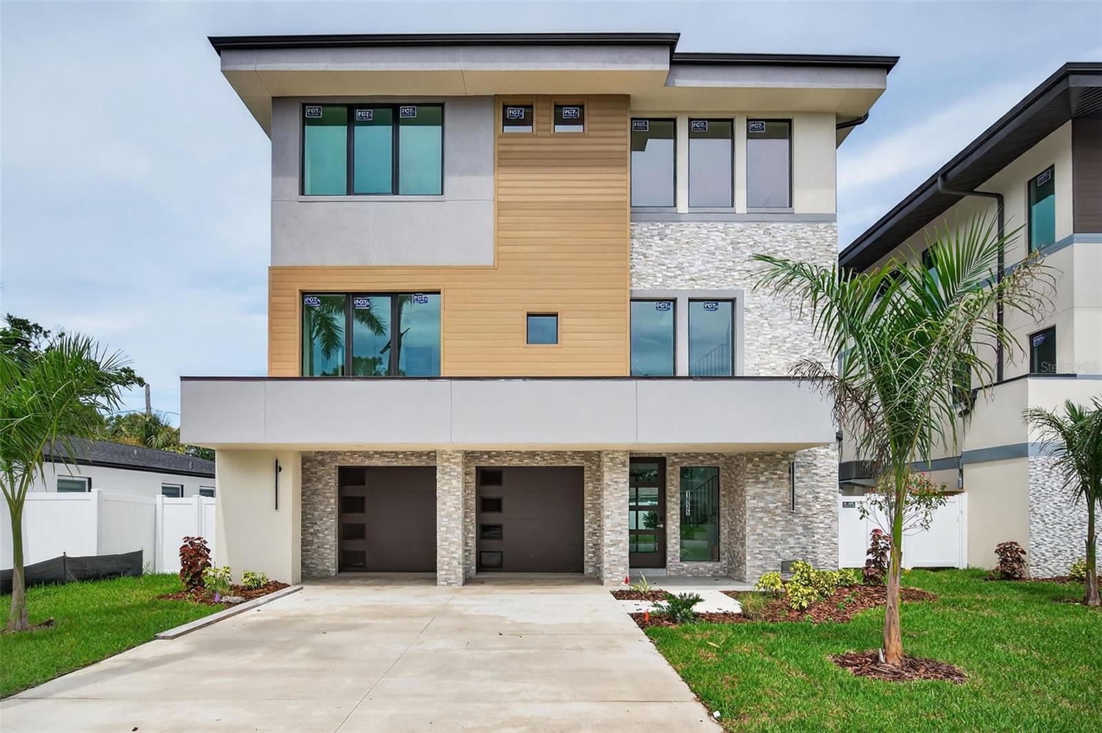 Another Magnificent Kelner Home is now completed and is Move-In Ready! Along with it's next door sister home, Modern elegance meets comfort in this exquisite 4-Bedroom, 3.5 Bathroom home. Discover the epitome of contemporary living in this stunning 2,926 sq. ft. modern home. Nestled within a serene neighborhood, this architectural marvel boasts a harmonious blend of sleek modern design, premium finishes, and thoughtful functionality. From the moment you step inside, you'll be captivated by the luxurious features that redefine modern living. Entertain and create culinary masterpieces in the state-of-the-art kitchen, complete with 42" cabinets and quartz countertops that glisten under the ambient LED lighting. Stainless steel appliances beckon culinary creativity while the walk-In pantry ensures your your ingredients are within easy reach and the kitchen stays clutter-free, making meal preparation efficient and easy. The large kitchen island seats 4 easily. There is storage under both sides of the island and cleanup is a breeze using the imbeded stylish farmhouse style sink. The home's open-concept layout seamlessly connects the living, dining, and kitchen areas, forming a hub of togetherness. Open the huge 3 panel sliding glass wall leading to the large lanai to create the perfect combination of refined indoor and outdoor entertainment spaces. Enjoy peace of mind knowing your home is equipped with high quality, PGT aluminum framed hurricane impact windows, combining safety and aesthetics. Four generously sized bedrooms provide private retreats for every member of the household. The immense master suite is a haven of tranquility featuring a double vanity and a luxurious glass-enclosed shower. Every detail has been meticulously designed, from the contemporary LED lighting that bathes the interiors in a warm glow to the modern fixtures that add a touch of sophistication to each room. Step outside onto the lanai and step into your own personal paradise. The lush landscaping envelopes the property, creating a serene and inviting ambiance. Imagine evenings spent on the patio, savoring the tranquil surroundings or hosting memorable gatherings with loved ones. Energy-efficient LED lighting illuminates every corner, enhancing the modern ambiance of the home. This modern masterpiece is not just a home; it's a lifestyle. Embrace the fusion of modern design, comfort, and luxury in every aspect of this 4-bedroom, 3.5 bathroom gem. Your future awaits – a harmonious retreat where every detail has been meticulously crafted to elevate your living experience. And remember, this isn't just any home, it's a Kelner Home.