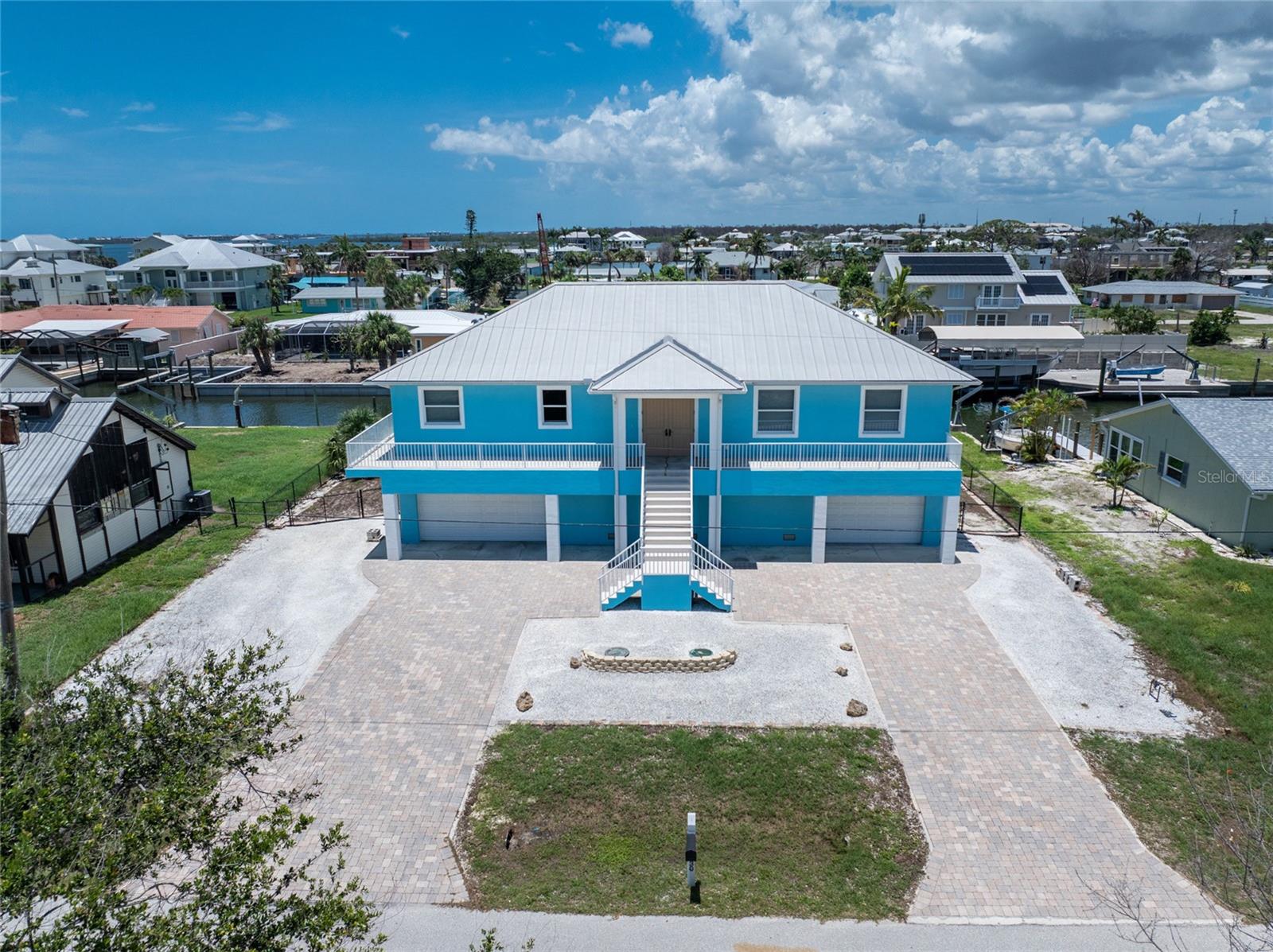 This WATERFRONT - NO BRIDGES TO BAY - HOME IS BUILT LIKE A FORTRESS! Concrete block stucco construction all the way up, with poured slab concrete flooring, and a METAL roof! Impact doors and windows! Finished floor elevation is over 18 feet, so flood insurance will be very affordable. Don't worry about all the steps as there is an elevator. With 100' ft of seawall and a covered 7000# boat lift, you can walk right out of your home, jump in the boat, and be in Lemon Bay in minutes, with fast access to Stump Pass and the Gulf of America! Very open great room design floor plan allows furniture placement in all kinds of different configurations! The kitchen features maple cabinetry, and solid surface countertops, and pantry for extra storage. Stainless appliance package includes: smooth top stove, dishwasher, built in microwave, and French door refrigerator. (all Kenmore) Laundry room is handily located just off the kitchen, and includes Kenmore front load washer and dryer. The primary bedroom has a walk in closet, ceiling fan, and ensuite bath, with double vanities w/solid surface countertops and a step in shower with easy clean solid surface walls. Guest bedrooms both have ceiling fans and walk in closets, and share a Jack and Jill bathroom, which features a combo tub/shower w/solid surface walls, linen closet, and vanity w/double basins. Each bedroom has it's OWN AC CONTROL PANEL AND ZONE! Half bath is conveniently located just off the Great room. The existing stained concrete flooring provides an opportunity to install whatever kind of flooring you like. Home is equipped with both central vacuum and a security system. Water heater was new in 2024, and AC system in 2020. Huge garage has all the storage you may need, with two automatic garage door openers. Catch some rays in your Pretty Pebbletec pool with paver decking. There's a 1300 gallon cistern that is filled from rainwater, providing an easy and inexpensive way to fill the pool or water your plants! Huge covered area downstairs would be just perfect for an outside kitchen. This home sustained NO HURRICANE DAMAGE AT ALL FROM HURRICANE IAN, and only about 27" of water in the garage from Milton. (concrete block walls made for easy cleaning!) Call today for your private appointment to see this home!