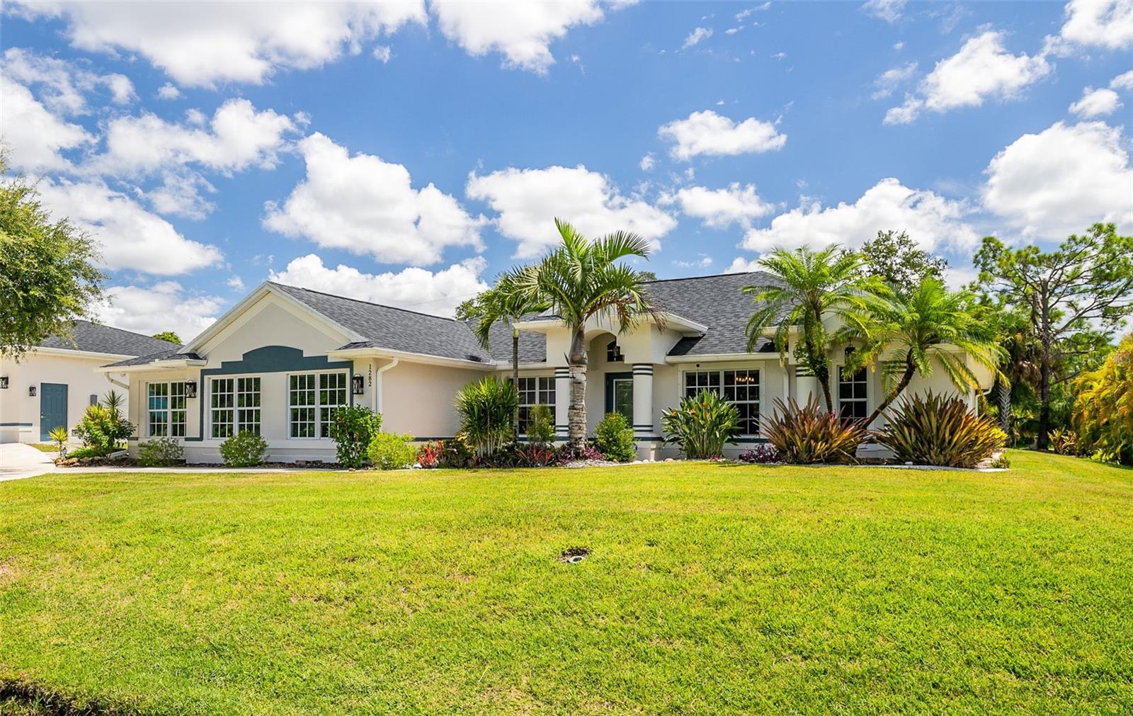 Experience the perfect blend of elegance and functionality in this extraordinary Port Charlotte retreat, nestled on 1.29 meticulously landscaped acres. With 2,951 sq. ft. of living space, a detached 6-car garage, and resort-style outdoor living, this estate is designed for those who value both sophistication and comfort. From the moment you arrive, the curb appeal is undeniable. A long, stone-accented walkway guides you through manicured tropical landscaping, setting the tone for the serene lifestyle this property offers. Inside, soaring ceilings and expansive living areas welcome you home. The open floor plan seamlessly connects the living room, formal dining, and kitchen, creating a perfect setting for entertaining guests. Luxurious finishes, warm tones, and abundant natural light give the interiors a refined yet inviting atmosphere. The primary suite is a true retreat, with a spa-inspired bathroom and walk-in closet. Four additional bedrooms provide space for family, guests, or a private office, spaces that adapt to your lifestyle. Step outside to discover your personal resort. The screened lanai and pool are ideal for relaxation or gatherings, while a thoughtfully designed firepit area offers the perfect spot for evening conversations under the stars. Mature landscaping and garden paths provide beauty and privacy in equal measure. Car enthusiasts and collectors will appreciate the oversized detached garage—room for six vehicles or a workshop or storage space. A basketball court and additional room to expand the possibilities for recreation and hobbies. Located just minutes from golf, Gulf beaches, world-class fishing, shopping, and dining, this property combines peaceful seclusion with unmatched convenience. For those seeking a home that embodies Florida luxury living with space to breathe and room to grow, this estate is a rare find.