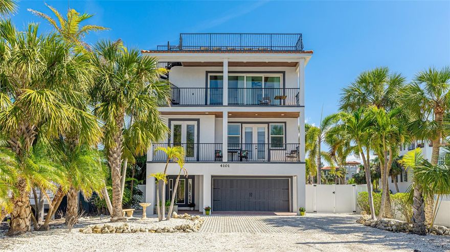 Tropical oasis on Anna Maria Island Beach View Retreat has expansive views of the Gulf and Intracoastal waterways. This custom-built home is not just a residence: it's a lifestyle. With quick access to the pristine beaches, vibrant local dining, live music, recreational activities, this property offers the perfect blend of relaxation and adventure. Experience an open and airy layout designed for relaxation and entertainment.  The great room features large windows, two sets of French doors that let the natural sunlight, highlighting the elegant finishes and coastal decor throughout enjoy sitting on the front porch watching the palm trees sway. Adjacent to the great room is a gourmet kitchen, complete with stainless appliances, ample cabinetry, and a spacious island that invites casual dining and social gatherings. Step outside to your private outdoor oasis, where you can unwind by the sparkling pool surrounded by a waterfall and lush tropical landscaping.  Lounge out in the sun from the rooftop deck and watch a sunset over the Gulf or enjoy panoramic views of the Intercoastal Waterway. The luxurious master suite provides a tranquil retreat, featuring expansive windows, French doors that lead out to the porch, enjoy the ensuite bathroom with a soaking tub and walk in shower, a spacious walk-in closet.  Additional bedrooms are thoughtfully designed to accommodate guest or family members, each with a porch and 3 with ensuite bathrooms.  Enjoy the 3+ car garage with 2 storage areas for all your beach and pool accessories.  For guest that need an elevator it has access to all floors. Bring your boat or jet ski this home has ample parking for your guest and toys.  Fantastic location with walking distance to Shops, Publix grocery store, drug stores and many local restaurants.  No need to drive with a Island trolley that runs every 30 minutes accessing most popular hot spots on the island and it is FREE!  This home comes turnkey furnished!