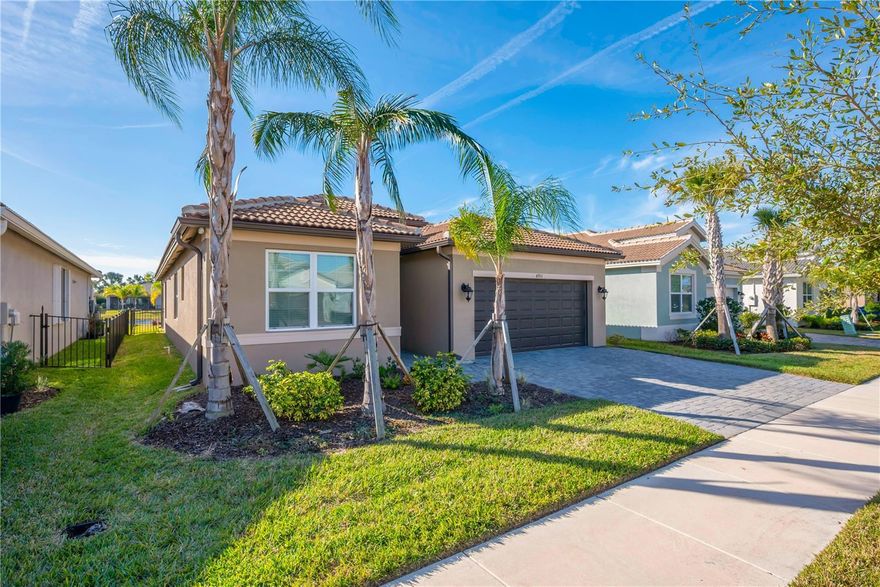 One or more photo(s) has been virtually staged. This highly sought-after Grenada floorplan features 3 bedrooms plus a spacious den that can easily be used as a 4th bedroom, 3 full baths, and a 2-car garage. As you approach, notice the brick paver driveway, barrel tile roof, and 8-foot decorative glass entry doors. Inside, the open, airy layout brings the great room, kitchen, and dining areas together. The great room provides direct access to the outdoor living area through an 8-foot glass slider that leads to an extended covered lanai with a serene water view — the perfect place to relax or entertain. The home showcases beautiful tile flooring throughout the main living areas and den. The luxurious kitchen features 42" white raised-panel cabinets, granite countertops, a subway tile backsplash, a large peninsula with a counter-height extended bar, an undermount stainless sink, and upgraded stainless appliances, including a GE French-door refrigerator. The primary suite is spacious with a coffered ceiling and two closets. The primary bathroom offers separate vanities with granite countertops, a walk-in shower with a seat and tile surround, and white cabinetry. Bedroom 2 has its own private en-suite bathroom for maximum guest privacy. The 3rd bedroom is tucked away from the main living areas and has easy access to it's own full bathroom. The den is ideal for a home office, media room, craft room, or an optional fourth bedroom. The laundry room includes upper cabinets, a utility sink, and washer/dryer hookups. This spectacular home is loaded with upgraded features such as impact glass windows and doors, a fenced yard, gutters, designer lighting, ceiling fans, crown molding throughout, and more. Experience vibrant 55+ living in Valencia Del Sol, a premier guard-gated community offering a resort-style lifestyle and an active calendar of clubs, activities, and social events. Residents enjoy a 25,000-square-foot clubhouse, resort-style pool, tennis and pickleball courts, fitness center, and on-site bistro — all included in the affordable HOA. From food truck nights and live poolside music to social dining groups, card games, arts and culture clubs, faith-based groups, and activities for outdoor and pet enthusiasts, there is always something to enjoy. Start living the resort lifestyle today at Valencia Del Sol. Call to schedule an appointment.