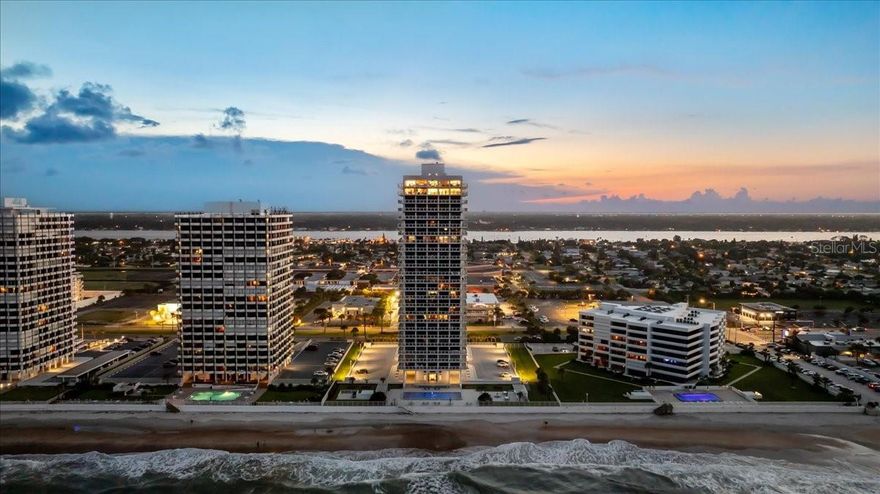 The Aliki Tower is a one of a kind direct oceanfront building, the likes of which cannot be found anywhere else from Jacksonville Beach to the Palm Beaches. Only 23 residents have the privilege of calling the Aliki Tower home. Each one of those residents owns their entire floor. The crown jewel of this 26 story building is the three level penthouse. In addition to its over 15,000 ft.², 4 bedrooms & 5 1/2 baths of unmatched living and outdoor areas, there are five underground parking spaces, two of which are in a self enclosed air conditioned garage w/ workshop area & additional storage. More storage exists in another private lower lobby storage room exclusive to this penthouse. On the first floor of this home-in-the-sky is the following: an open great room/kitchen concept featuring marble flooring throughout & a media wall. The kitchen is appointed with Thermador, Fisher & Paykel & Bosch appliances, Pedeni Italian cabinetry & an oversized island adorned with Jurassic Granite. Two spacious bedrooms with full ensuite baths & walk-in closets are located in the southwest & northwest corners of this floor. The first of two primary suites is located on this floor as well. This southeastern suite includes an oversized bedroom, large walk-in closet, double vanities, a jetted spa tub, large shower with steam & a Toto automated commode. Before ascending to the next floor via the staircase adorned with glass walls, marble treads & risers, make sure to visit the cantina. This refreshment & snack area, located behind the staircase, encompasses the kitchen pantry with tall cabinetry, multiple pullouts, refrigerator, coffee station, espresso machine, sink, ice-maker & a beverage refrigerator. The 25th floor of this singular offering includes the second private foyer & elevator landing with double glass entry doors. The entire southern half of this floor is the location of the grand primary suite. This suite's sleeping & sitting area is entered through double doors located off a foyer that separates it from the additional office, living, & entertaining area on the north half of this floor. This owners oasis includes a dressing room closet with extensive built-in organizers, a large flatscreen TV & a center storage island. Beyond this closet-of-envy is the grand bath. A spectacular steam shower & large jetted tub are enclosed behind a glass wall. Separate vanities, a water closet with automated Toto commode, an additional closet & laundry room exclusive to the grand primary suite complete the owners sanctuary. The 25th floor great room features a stone fireplace and remarkably it is wood burning! The 25th floor also features a galley kitchen with sink, microwave, & two burner Miele cooktop. Just off this second great room you will find another full bath with custom countertop, a marble basin, recessed LED lighting, shower & tub. Lastly, on this upper level is your second expanded wrap around balcony overlooking the sea. The west side of this balcony includes a private pet-relief area, a dry sauna, & a multi-person hot tub to soak in. Ascend the outdoor stairs to the roof top balcony complete with air rights. This upper deck features unparalleled 360° ocean and city views day & night. With 3 sunbathing islands, a built-in bar with a stone countertop, sink, refrigerator, large flatscreen TV, & a barbecue grill island, you can comfortably entertain over 200 of your closest family/friends. The features of this singular offering are too exhaustive to list.