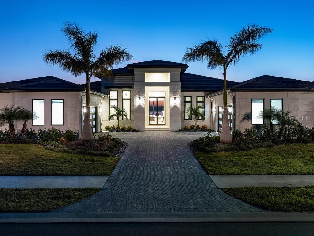 2025 Parade of Homes Winner! Custom Home Category and Best Residential Homes Finalist. Model Home List Price: $4,268,000 (Model Home Net of a Leaseback) plus $330,000 (Furniture Package) equals $4,598,000. Anchor Builders Martinique II fully furnished Model Home at Wild Blue at Waterside is now available to purchase with a leaseback.
The grand approach to this one-of-kind Transitional Model Home is highlighted by towering columns finished in Artic Hewn stonework and a horizontal louver shutter. A wide paver driveway accented with Royal Palm trees and artistic landscaping provides easy ingress and egress to the oversized 4 car garages. The extra wide Wild Blue 100' Lapis homesite provided custom home builder Roy Dupuis and their celebrated Residential Designer an exceptional opportunity to create a home that truly maximizes this homesite's spectacular big water and Sunset Views. The front of the home faces a private preserve.
The moment you step from the seashell paver Grand Entry through the custom iron 10ft high doors, your immediate sense of arrival is that of a calming, welcoming and inviting feel of sanctuary.
Your attention is immediately captivated by the uninterrupted sightline from the Foyer where you will welcome your guests to the spectacular lake view that elevates the tranquil and welcoming feel.
The Grand Room features vaulted ceilings with stained wood beams and stained wood archways, connected with wide galleries which invite you to each space with a beautiful blend of elegant, but soothing colors and textures. This comfort and warmth transcend throughout the Owner's Suite, Fitness Room, Study, three ensuite Guest Bedrooms, Powder Bath, and generously appointed Outdoor Living-Dining-Pool Area that blend seamlessly with the indoor spaces.
The Wild Blue at Waterside Clubhouse will provide residents fine and casual dining, social events and a well-appointed fitness center, classes, personal training, golf simulator, movie theatre and more. The shared Midway Sports Center will include 13 acres for neighbors to explore, play and connect. Miles of lakeside and preserve walking paths and trails, 6 tennis courts, 8 pickleball courts, sports pro shop, kayak launch, playground and of course, 2 dog parks for our fury friends ... All created for your next chapter nature-centric, active lifestyle!
The List Price INCLUDES all Furnishings, Artwork, and accessories which total $330,000. Interior Design and Furnishings by Riley Interior Design. The Sale will be subject to a Builder Leaseback. List Price is Net of a Leaseback.