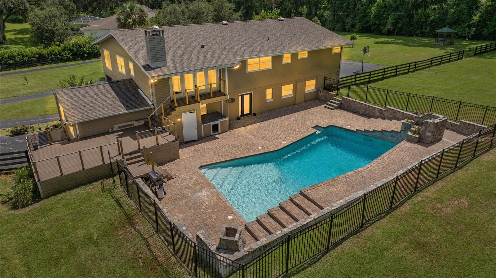 One or more photo(s) has been virtually staged. Welcome to your private retreat in the heart of Southeast Ocala. This stunning three-bedroom, three-bathroom home offers just under 4,000 square feet of beautifully updated living space, nestled on 1.90 acres of A1-zoned land—giving you the freedom and flexibility to enjoy the lifestyle you’ve been dreaming of, whether it’s gardening, keeping animals, or simply soaking in the serenity of a spacious property. Tucked behind a private entry, the home feels like a peaceful escape while still being just moments from Publix, shopping, dining, and other everyday conveniences. Inside, you’ll be greeted by warm luxury vinyl plank flooring that flows throughout, setting the tone for comfort and style. The first floor features a spacious guest bedroom and full bathroom, a cozy living room anchored by a fireplace, and a versatile flex space that’s perfect for a playroom, home office, or creative studio. Upstairs, the home continues to impress with a second living room and formal dining area that provide additional space to gather and relax. The heart of the home is the stunning remodeled kitchen, designed for both form and function, featuring dual islands, Corian countertops, new stainless steel appliances, and abundant cabinetry that makes entertaining and everyday living effortless. The primary suite offers sweeping views of the grounds and a spa-inspired bathroom with two completely separate wings—each with its own walk-in closet and vanity—connected by an oversized, standalone shower that creates a luxurious retreat. Another generously sized upstairs guest bedroom includes its own private bathroom, offering comfort and privacy for family or overnight guests. Step outside and you’ll fall in love with the resort-style backyard, highlighted by a showstopping 55,000-gallon pool with a waterfall feature and a multi-level deck perfect for sunbathing, grilling, or hosting unforgettable get-togethers. A chicken coop and designated play area add to the charm and functionality of this special property, while mature trees and landscaping provide privacy and natural beauty at every turn. With a new roof installed in 2021, two new air conditioning units, a new hot water heater, and all-new appliances, this home is as move-in ready as it is remarkable. Blending luxury, comfort, and the charm of country living—all within city reach—this is a one-of-a-kind opportunity to own a home that truly has it all.
